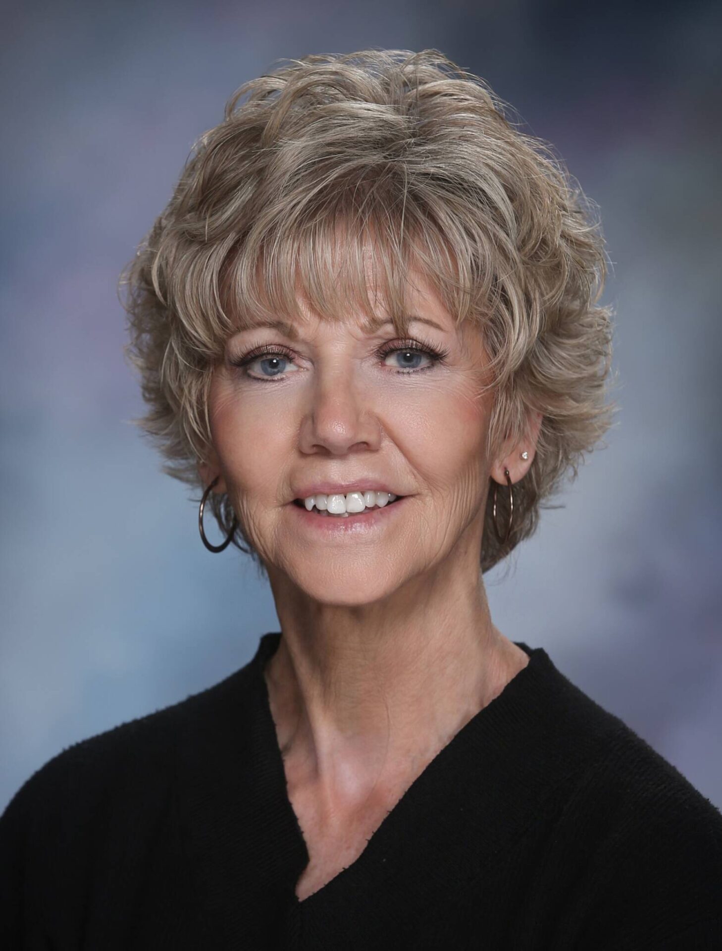 Portrait of Anita Saas, professional woman with short blonde hair, smiling confidently.