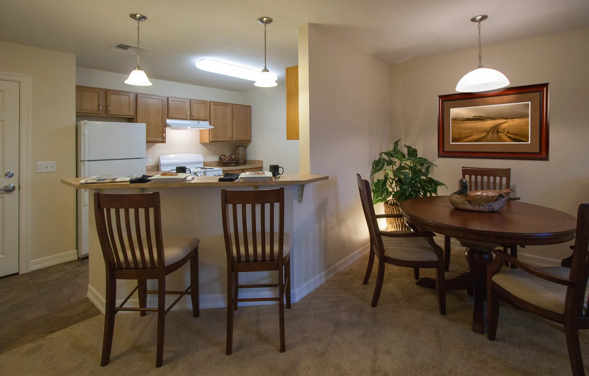 Bright kitchen with white appliances and wooden cabinets, open to a cozy dining space.