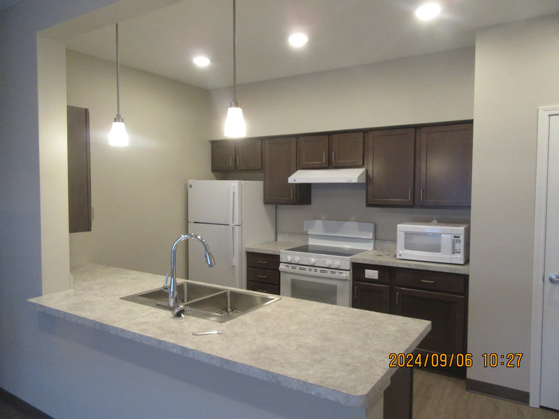 Modern kitchen with dark wood cabinets, white appliances, and a spacious countertop.