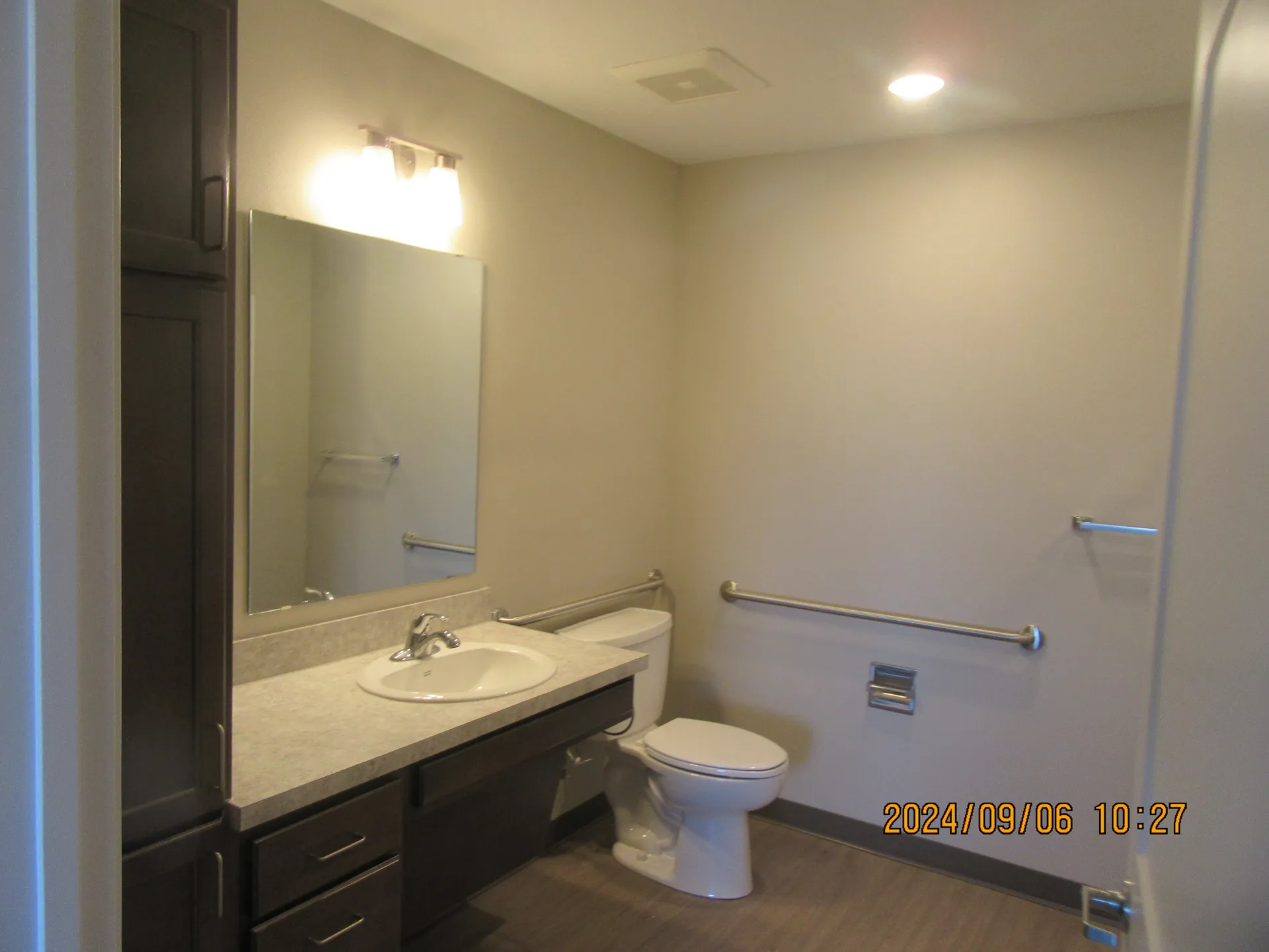 Accessible bathroom with grab bars, sink, and toilet for improved safety.