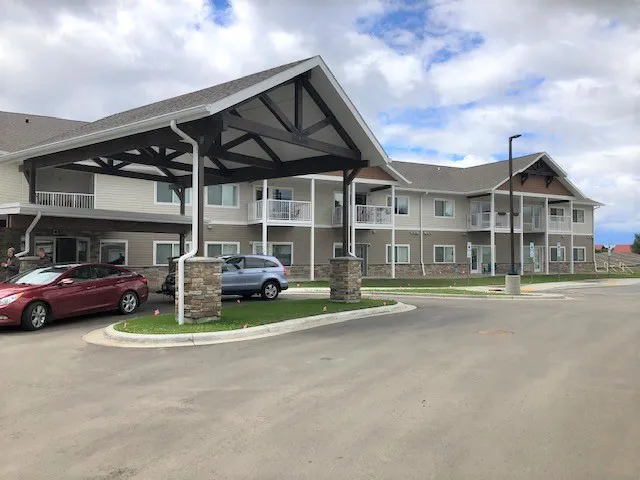 Apartment complex with covered parking, balconies, and landscaped grounds.