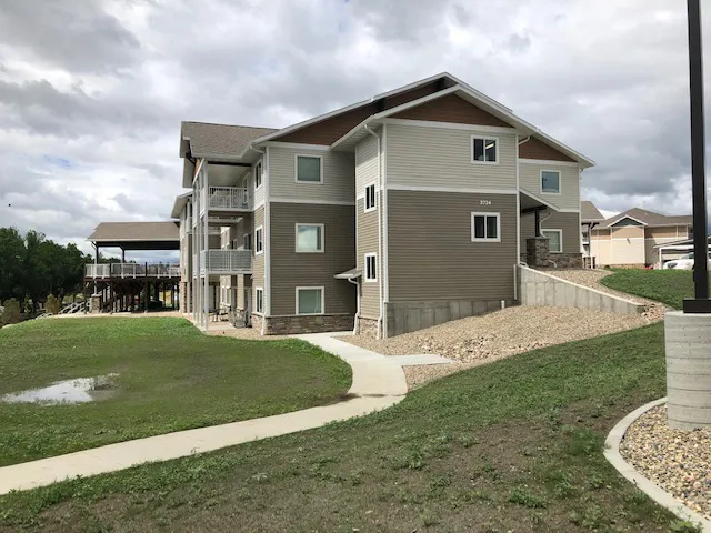Modern multi-story residential building with balconies and landscaped surroundings.