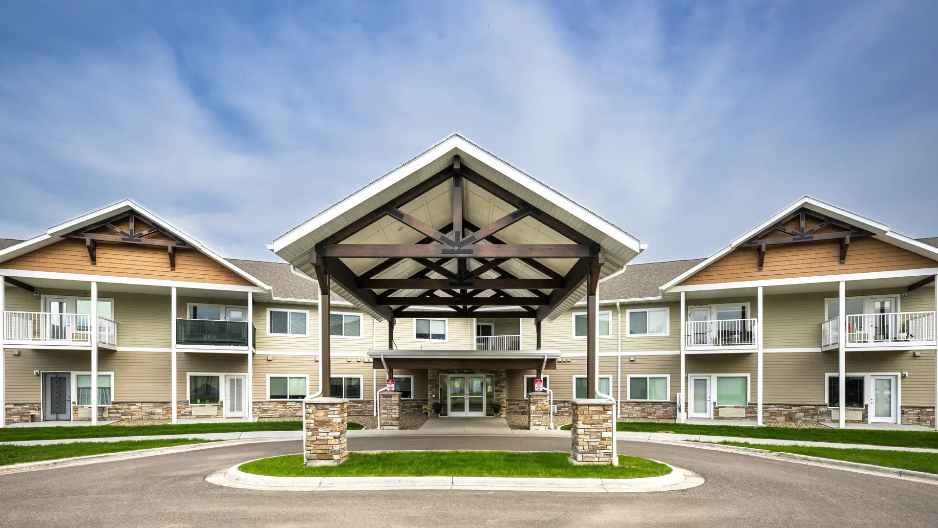 Modern apartment complex with a central covered entrance and landscaped surroundings.