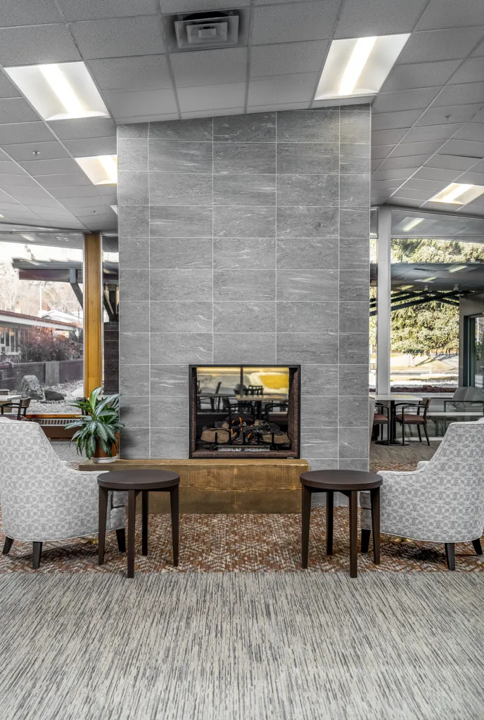 Modern lobby fireplace with cozy seating area and large windows for natural light.