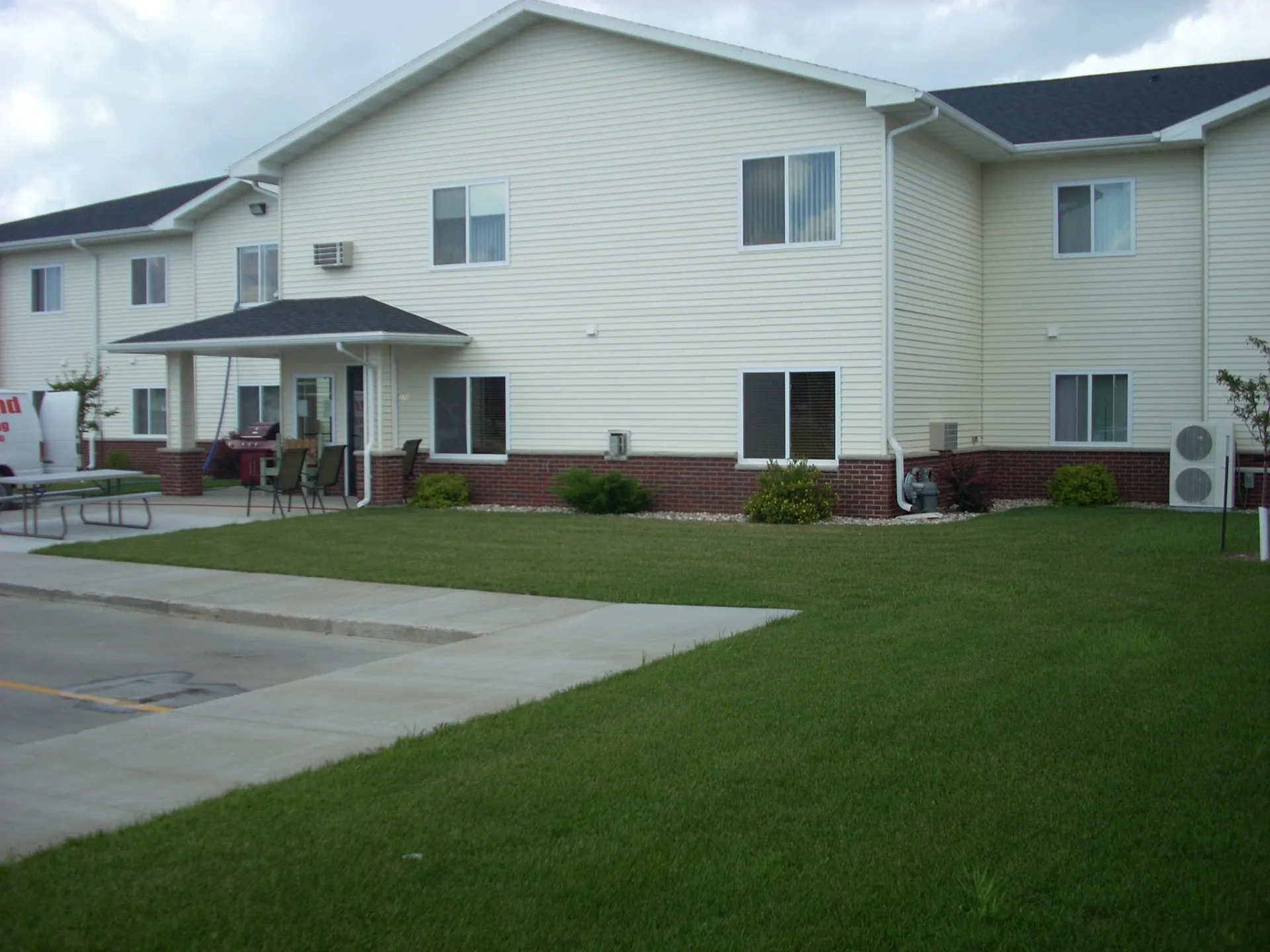 Apartment building with outdoor seating and green lawn.