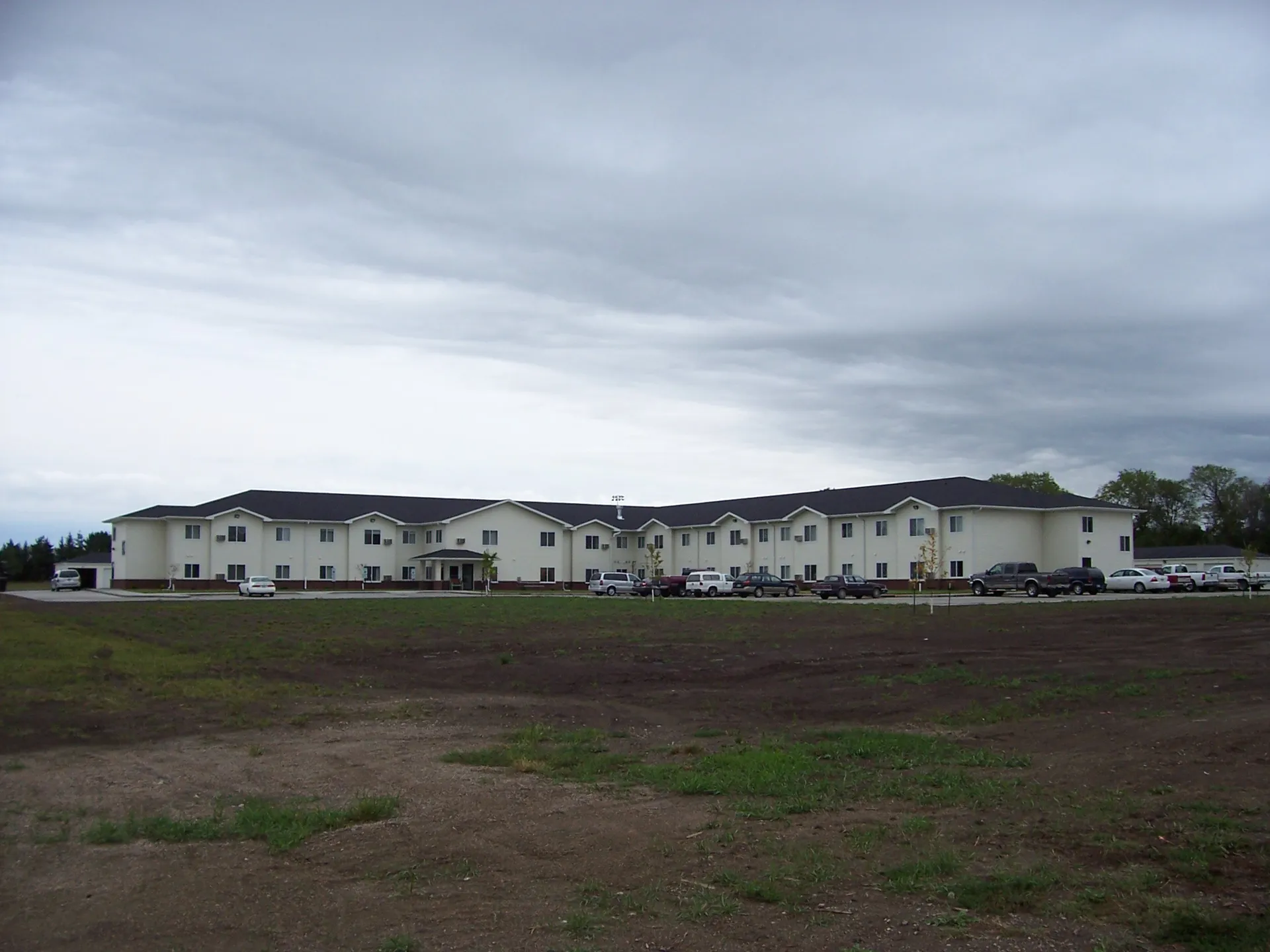 Apartment complex with multiple units and parking lot on a cloudy day.