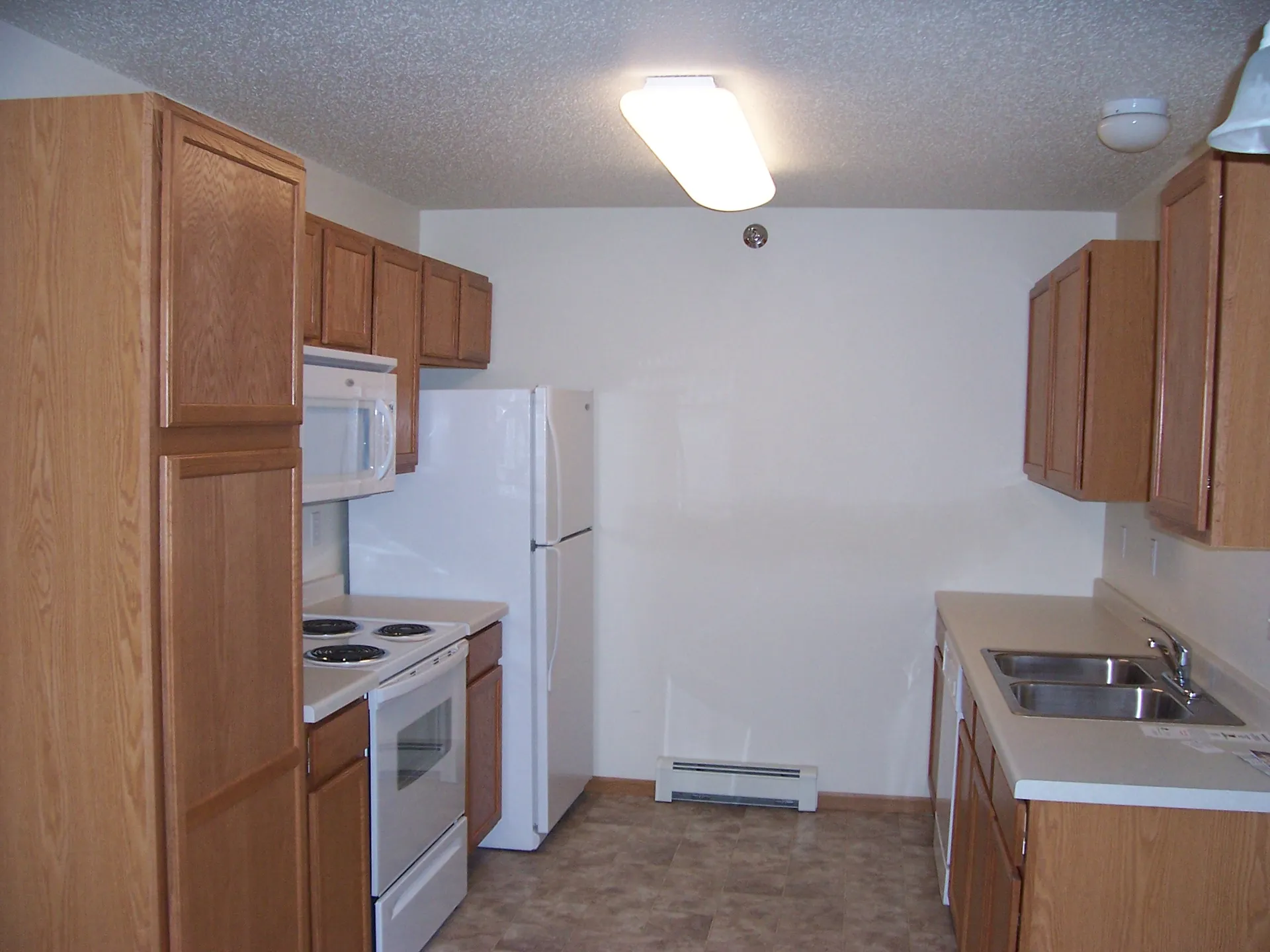 Kitchen renovation featuring wooden cabinets, white appliances, and updated fixtures by CR Builders.