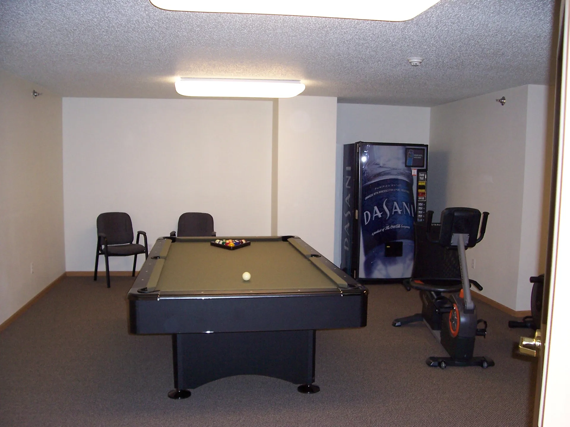 Pool table with cue ball and balls in a game room setting.