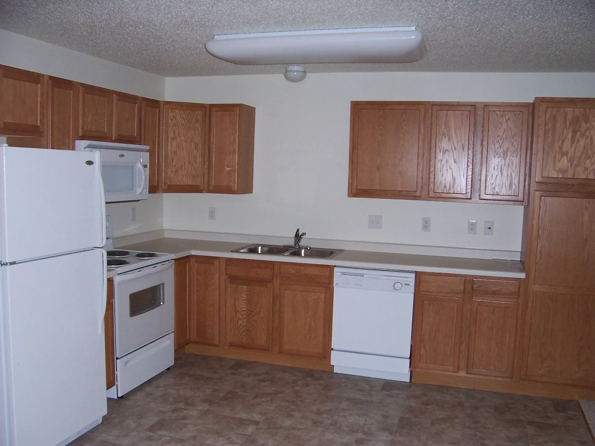 Kitchen with wooden cabinets and white appliances.