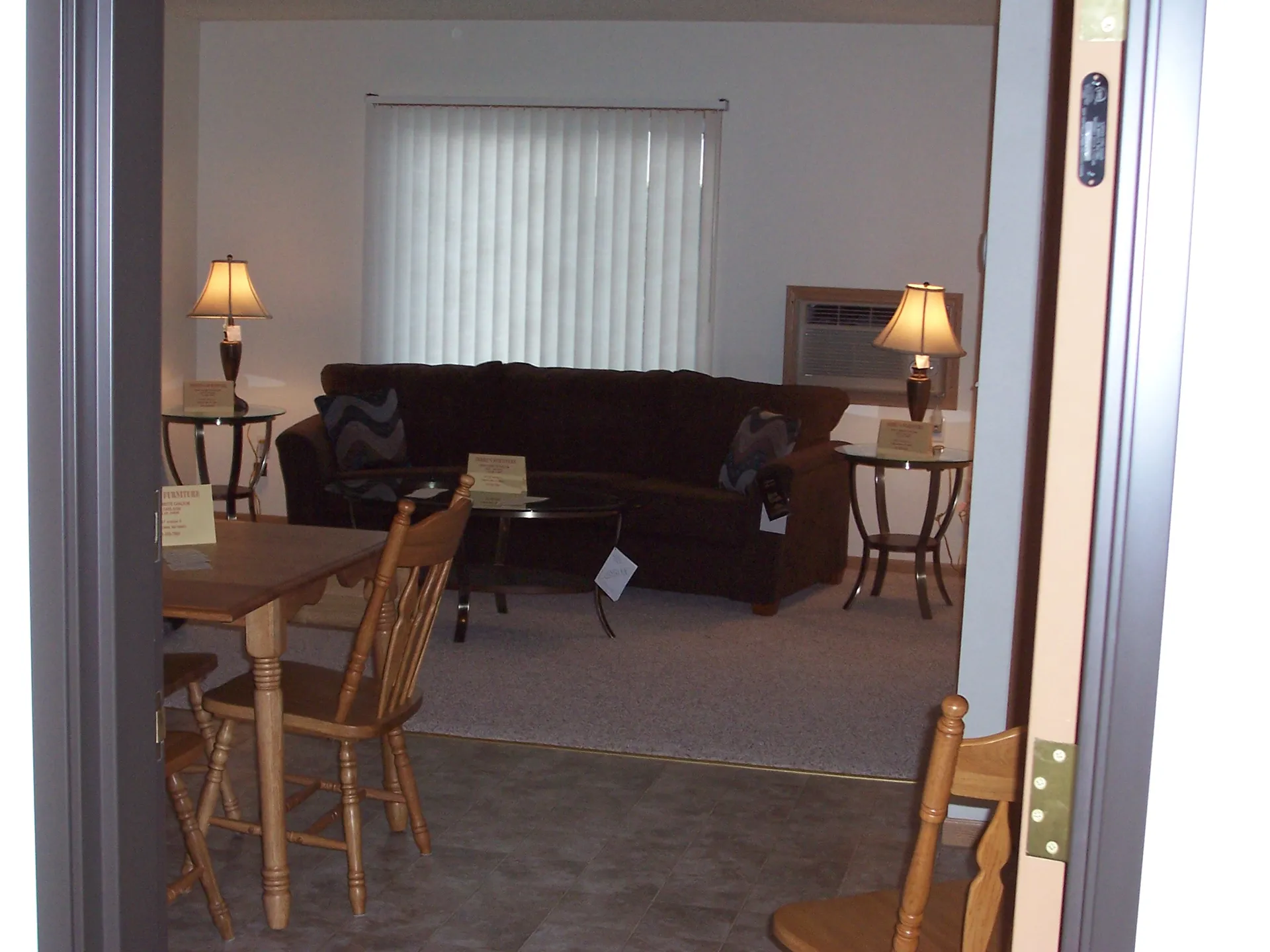 Cozy living room featuring a sofa, wooden chairs, and warm table lamps for a welcoming atmosphere.