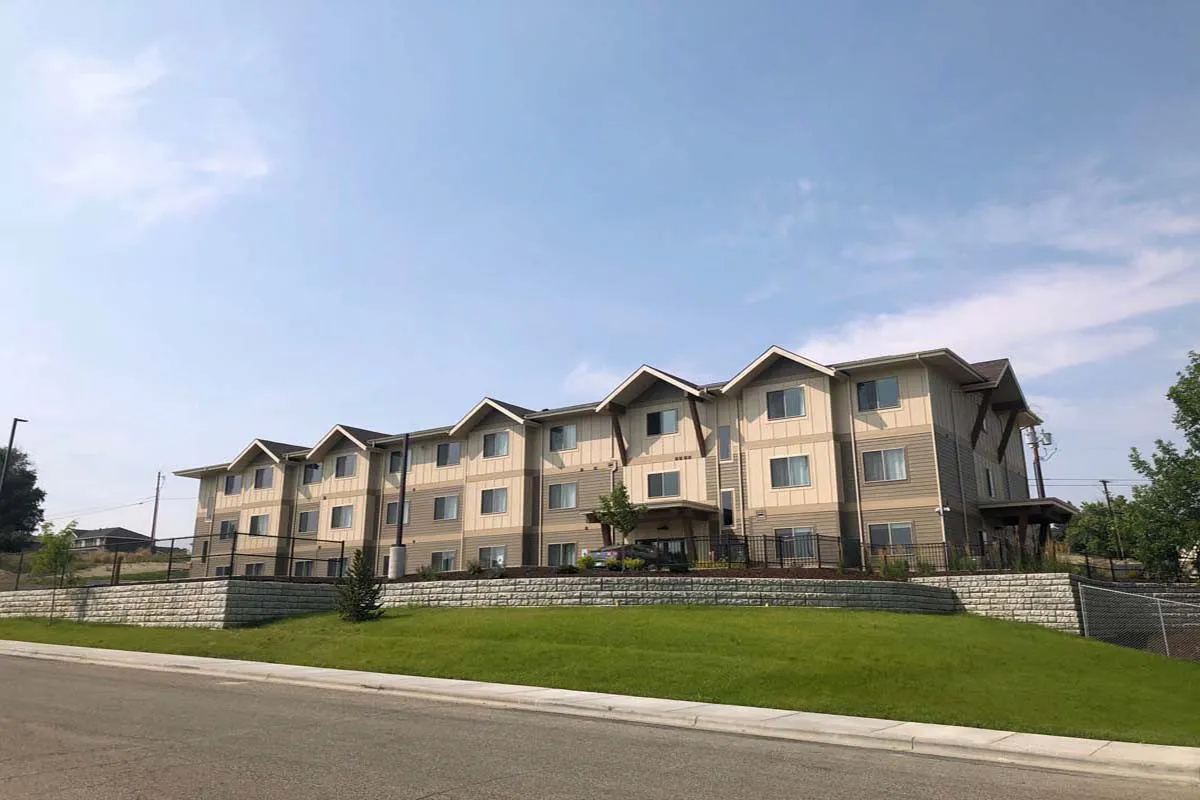 Multi-family residential building with landscaped yard and blue sky.