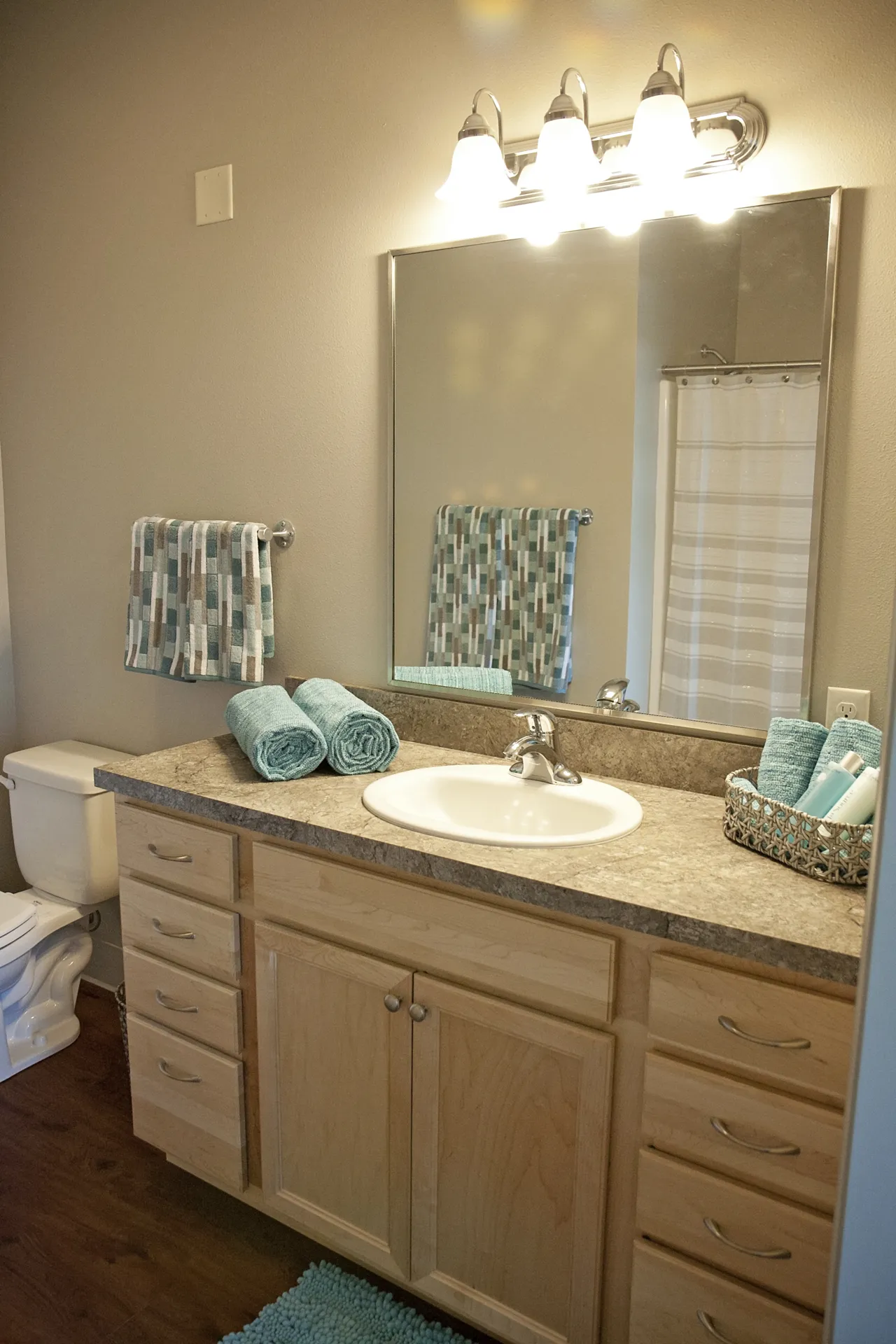 Modern bathroom vanity with granite top, large mirror, and organized towels.