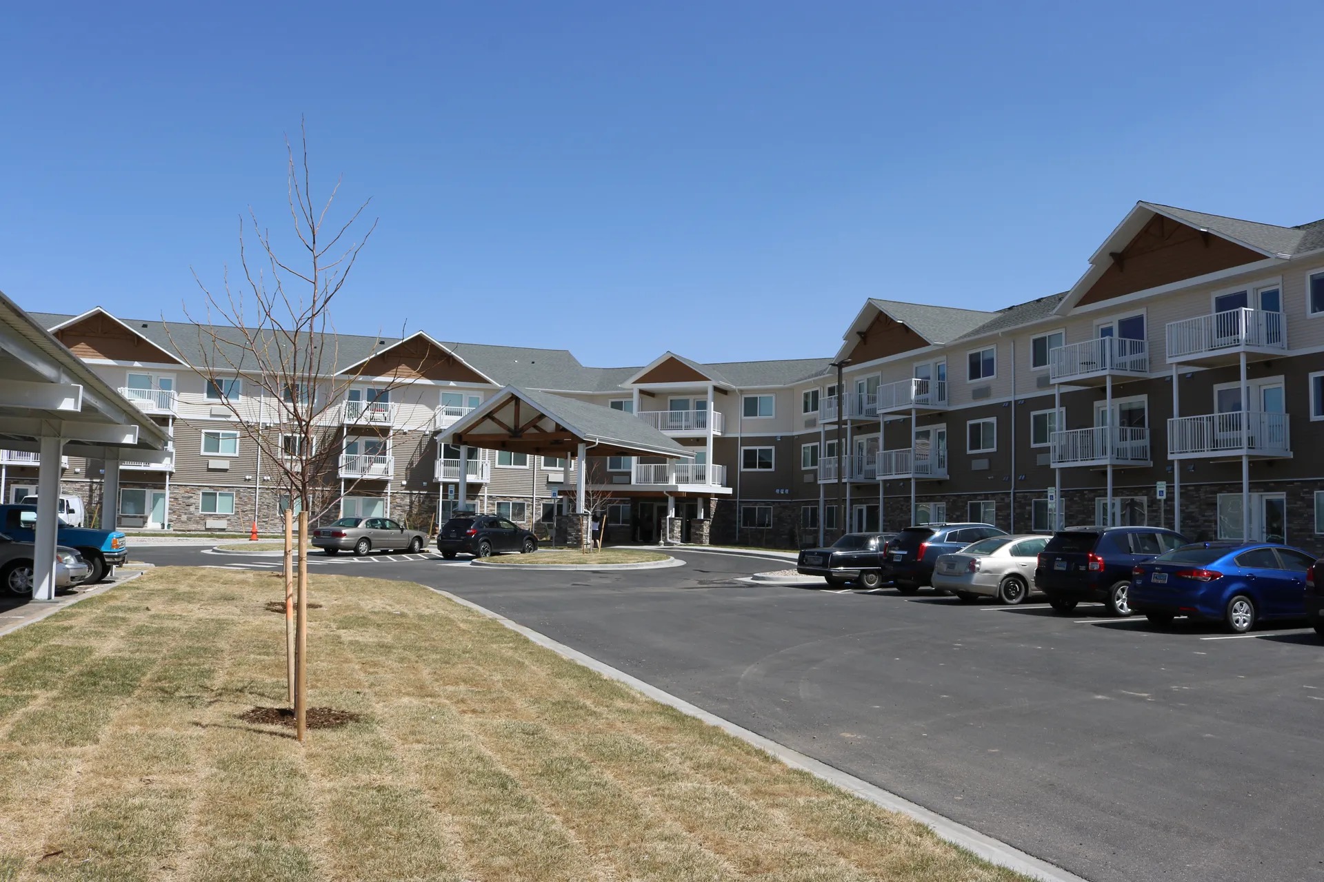 Apartment complex with parking area and landscaped yard for residents.