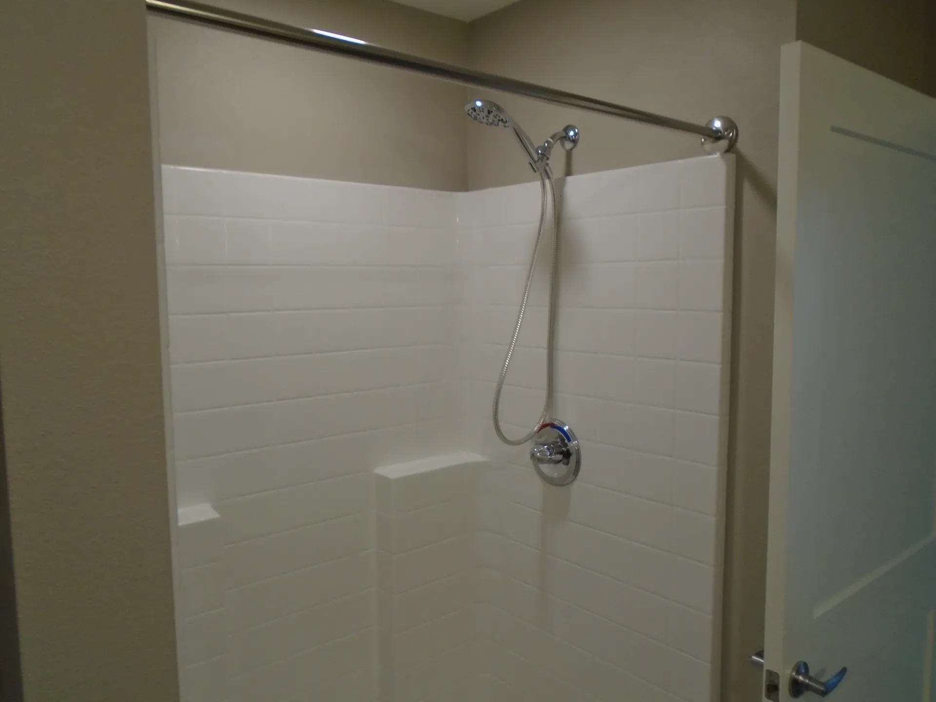 Modern bathroom shower with white tile walls and chrome fixtures.