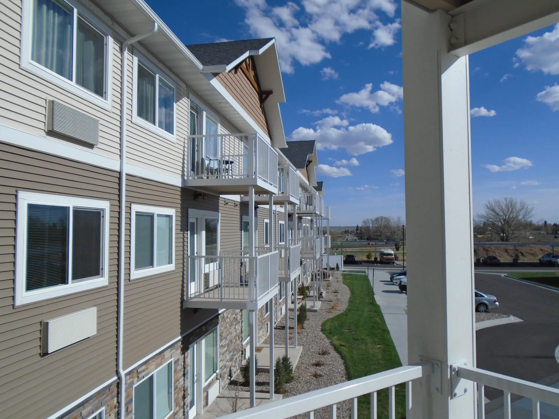 Apartment building with balconies, modern design, and landscaped outdoor area.