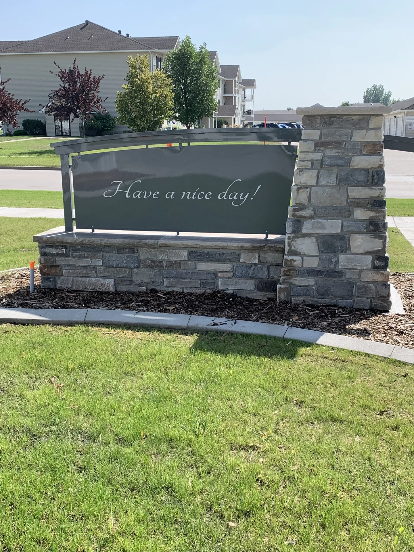 CR Builders outdoor sign with stone base and greenery.
