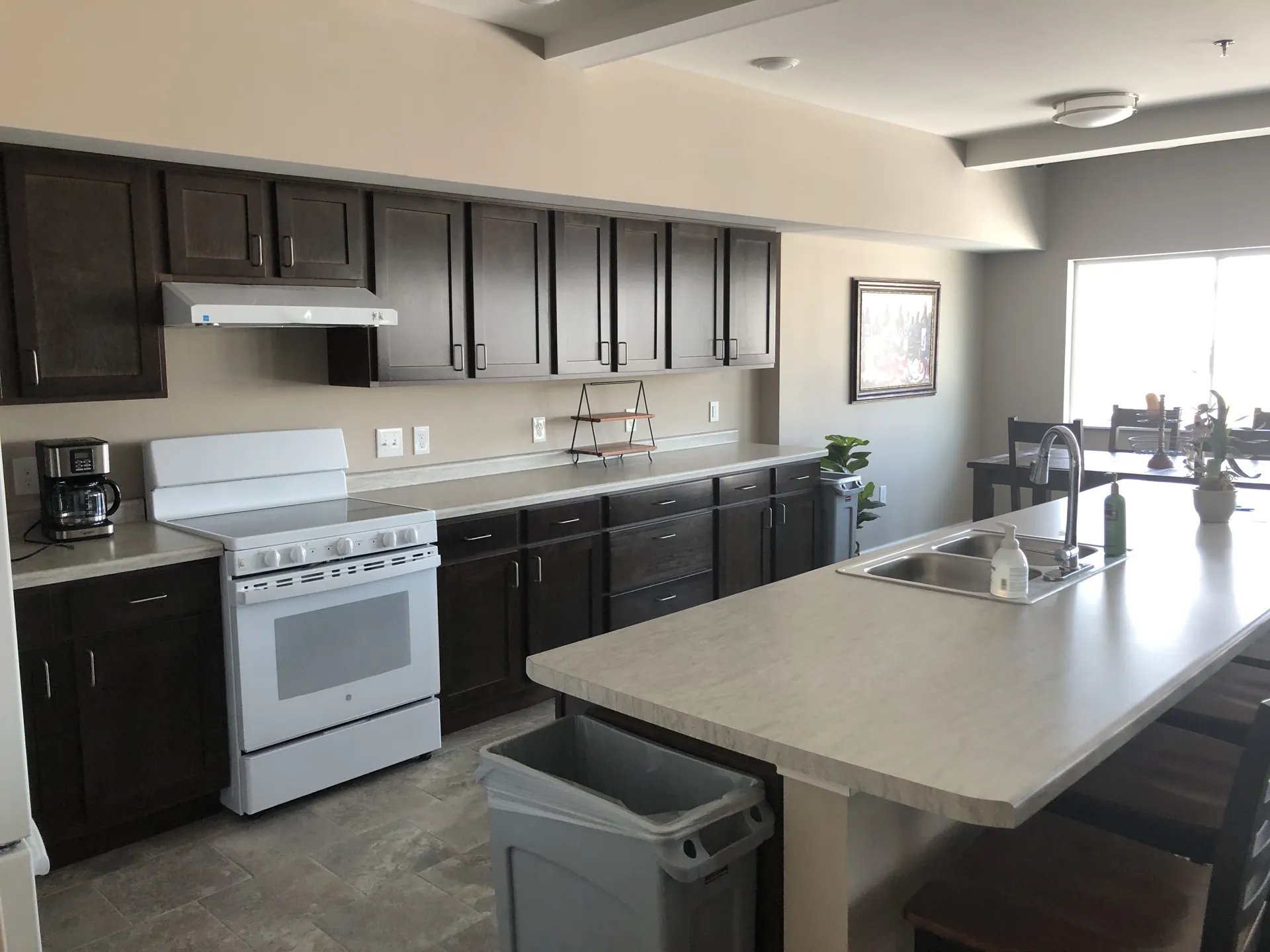 Kitchen with dark cabinets, white countertops, and stainless steel sink.
