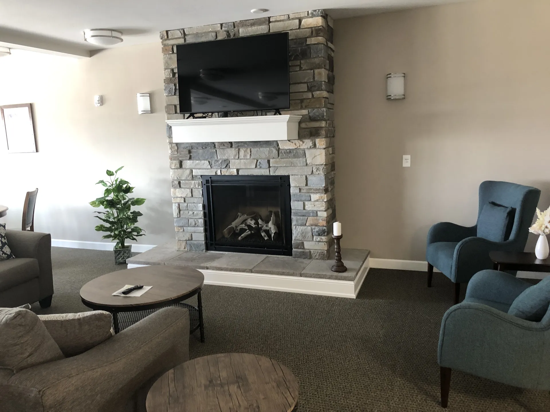 Cozy living room featuring a stone fireplace, flat-screen TV, and stylish armchairs for relaxation.