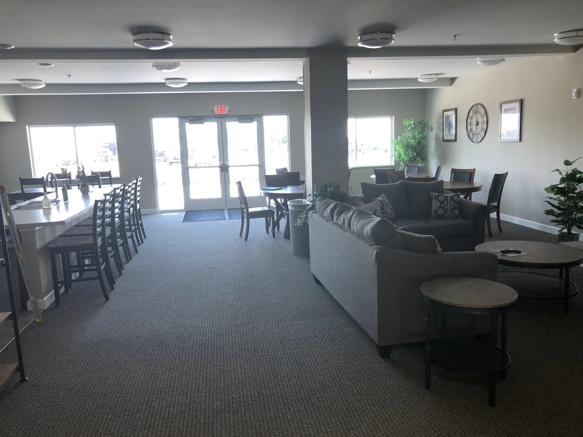 Comfortable lounge with sofas, tables, and natural light in a professional setting.