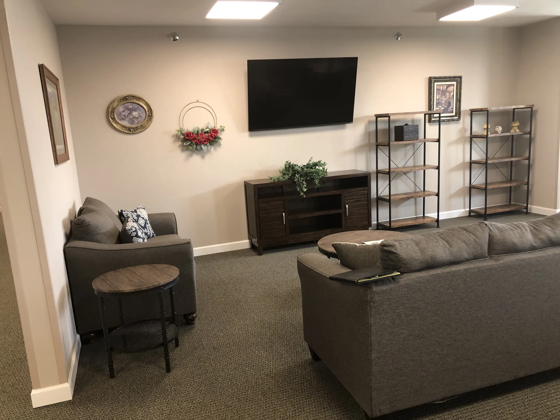 Modern living room with wall-mounted TV, decorative shelves, and cozy seating area.