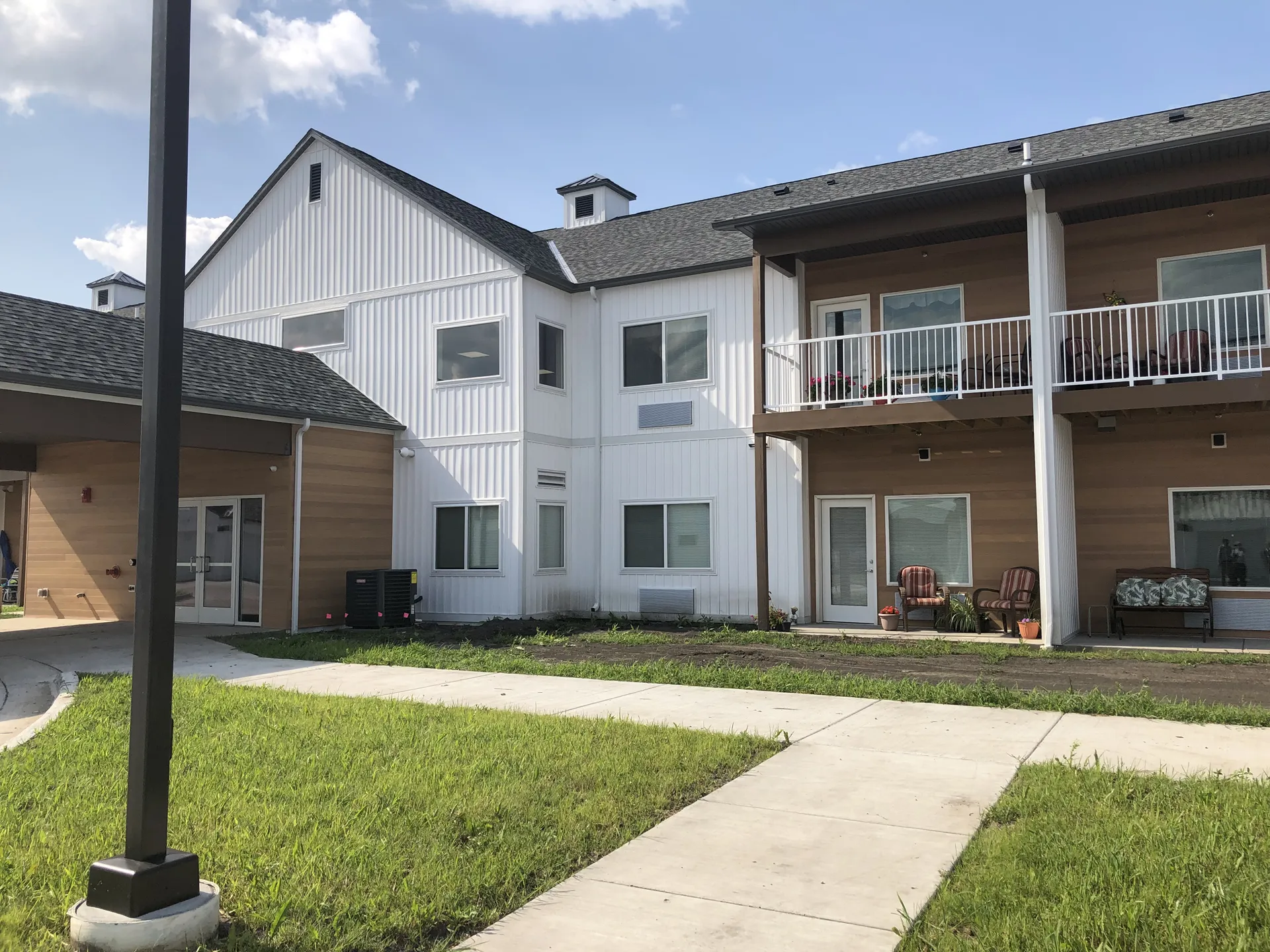 Apartment complex with balconies, modern design, and well-maintained lawn.