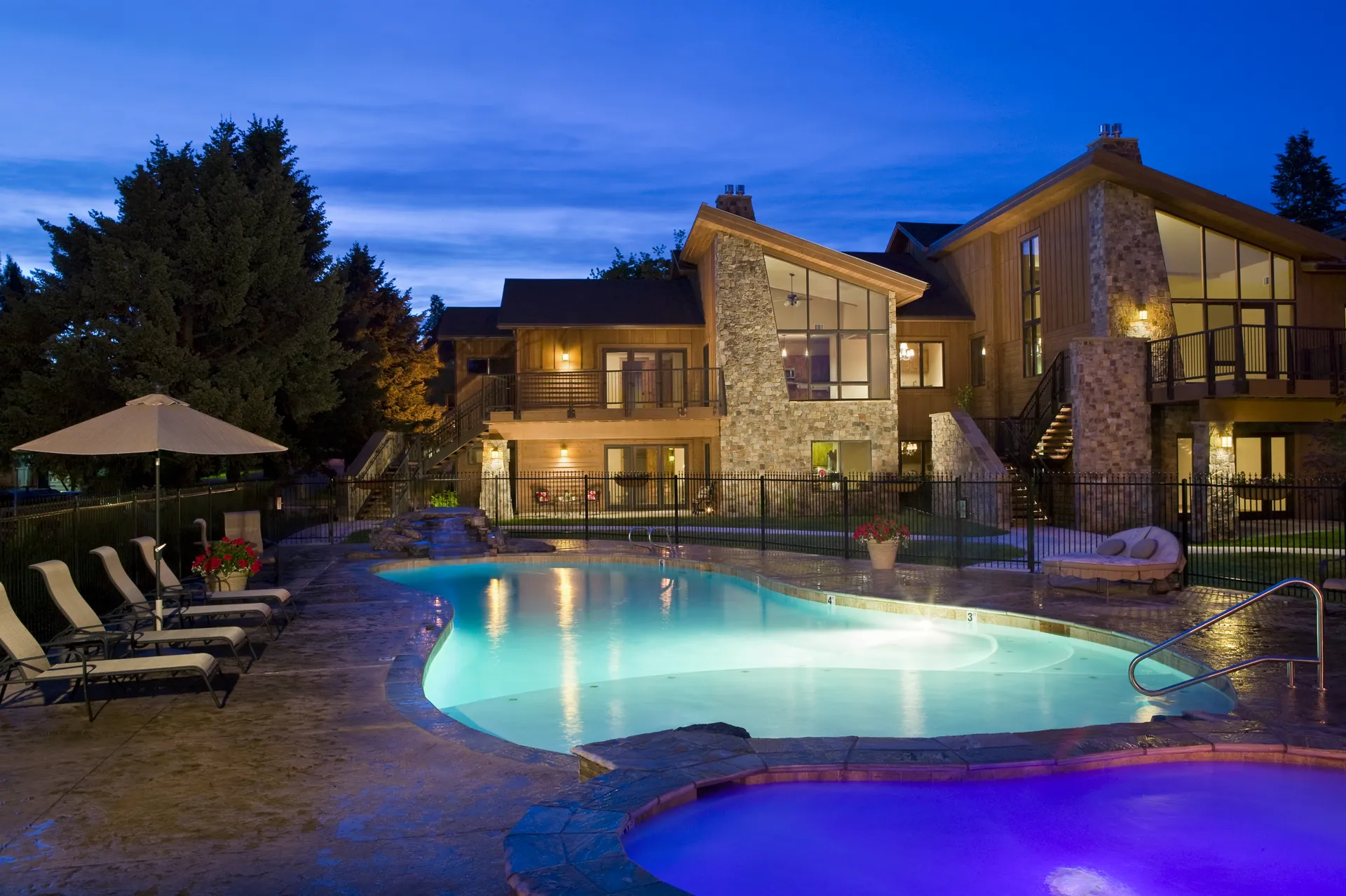 Modern house with illuminated swimming pool and outdoor lounge area at dusk.