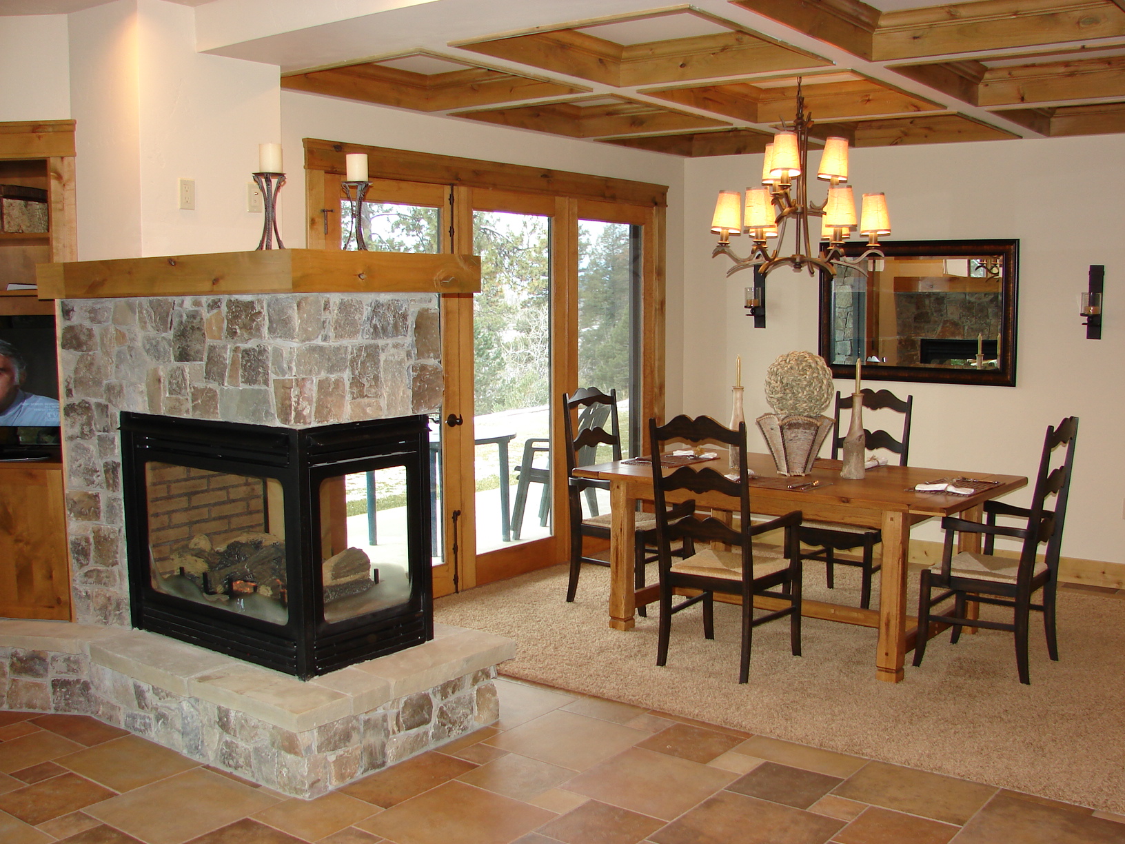 Cozy rustic dining room featuring a stone fireplace, wooden accents, and large windows for natural l.