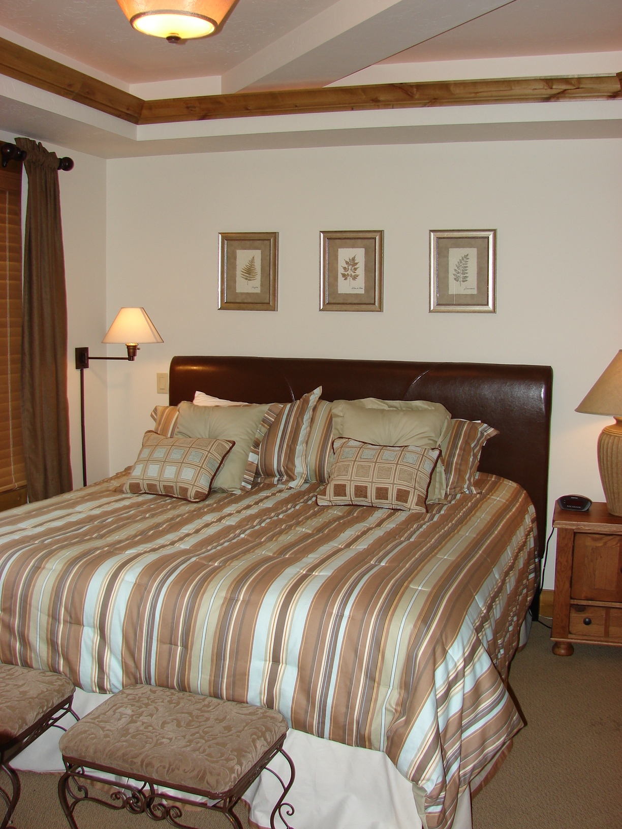 Comfortable bedroom featuring a large bed with striped bedding and decorative pillows. Warm lighting.