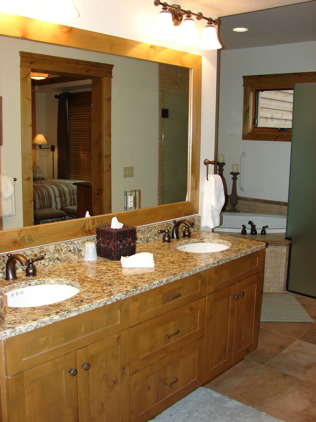 Bathroom vanity with dual sinks, granite countertop, and large mirror in a modern home.