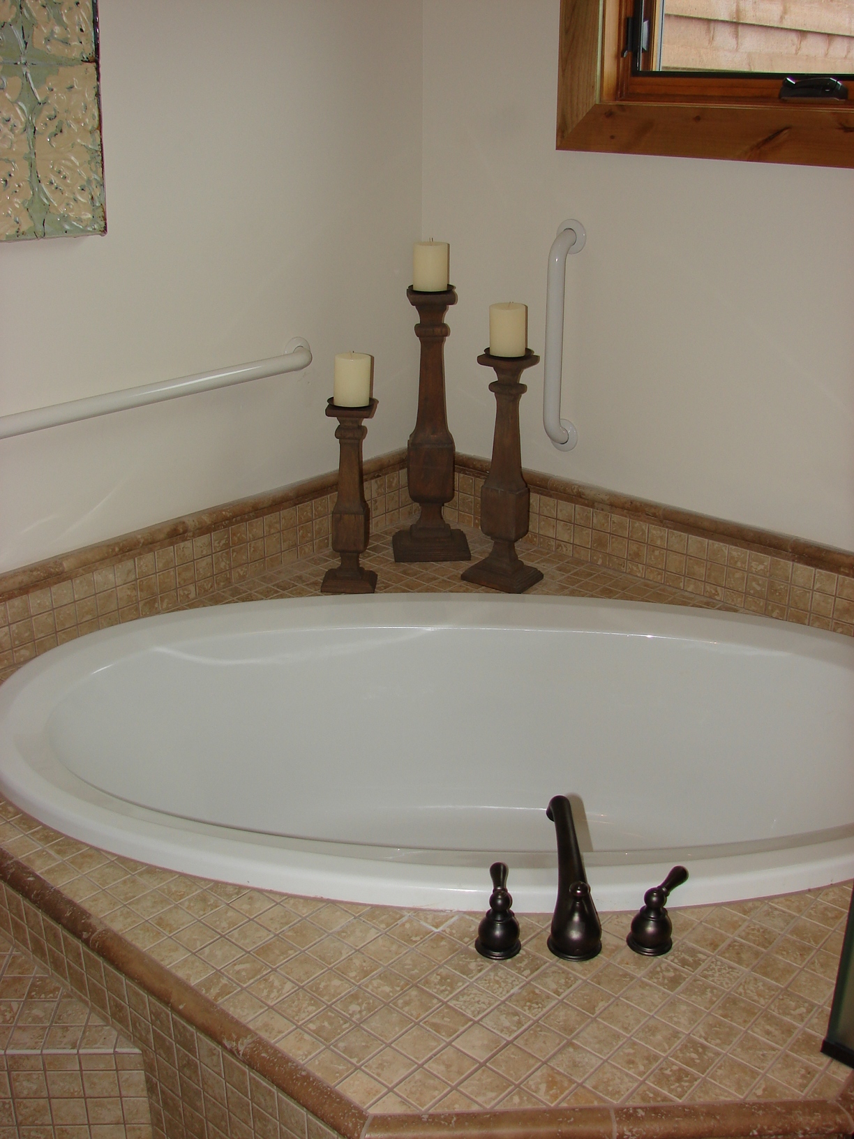 Modern bathtub with candles and window in a cozy bathroom setting.