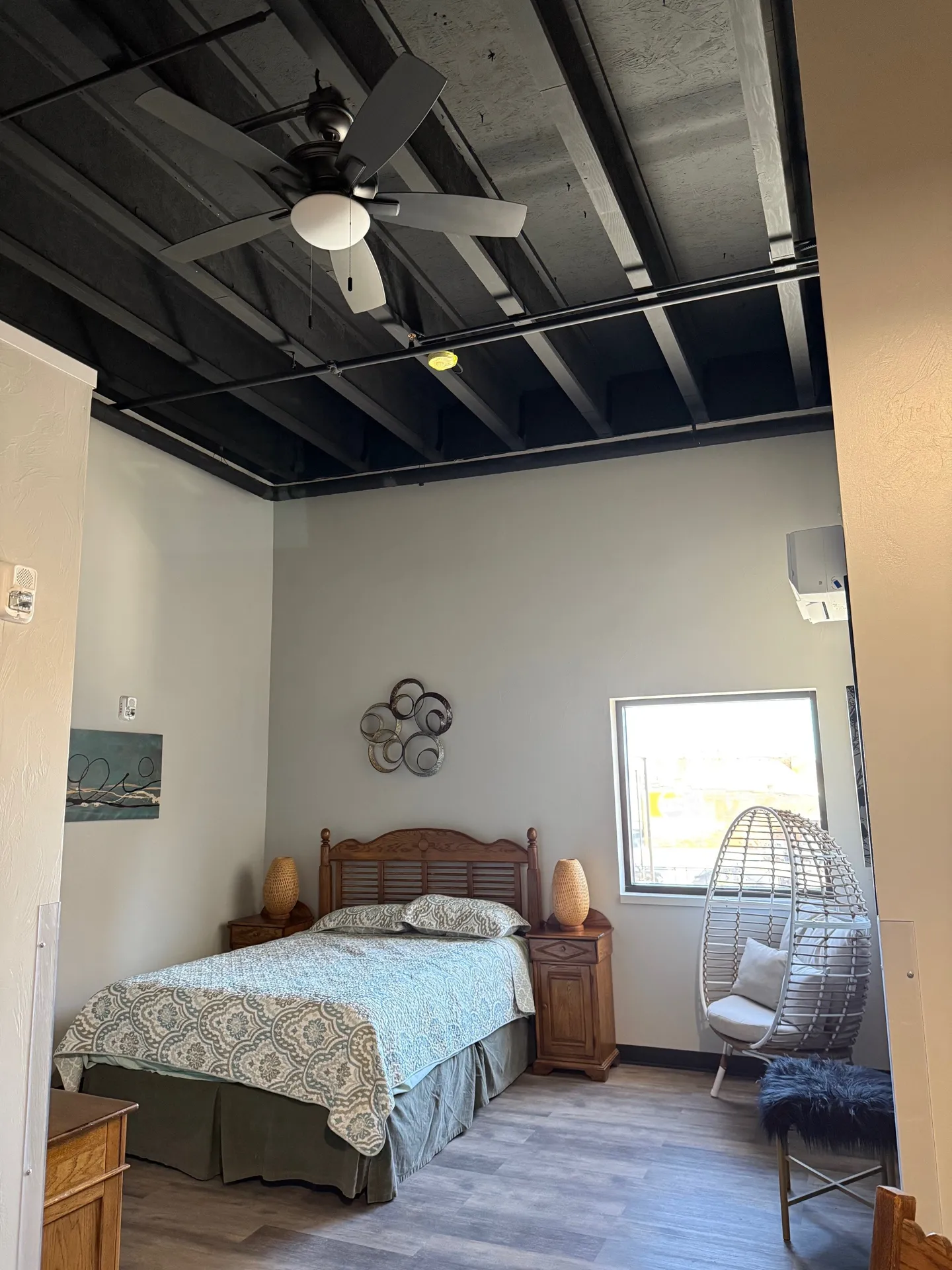 Modern bedroom with wooden bed, ceiling fan, and contemporary decor.