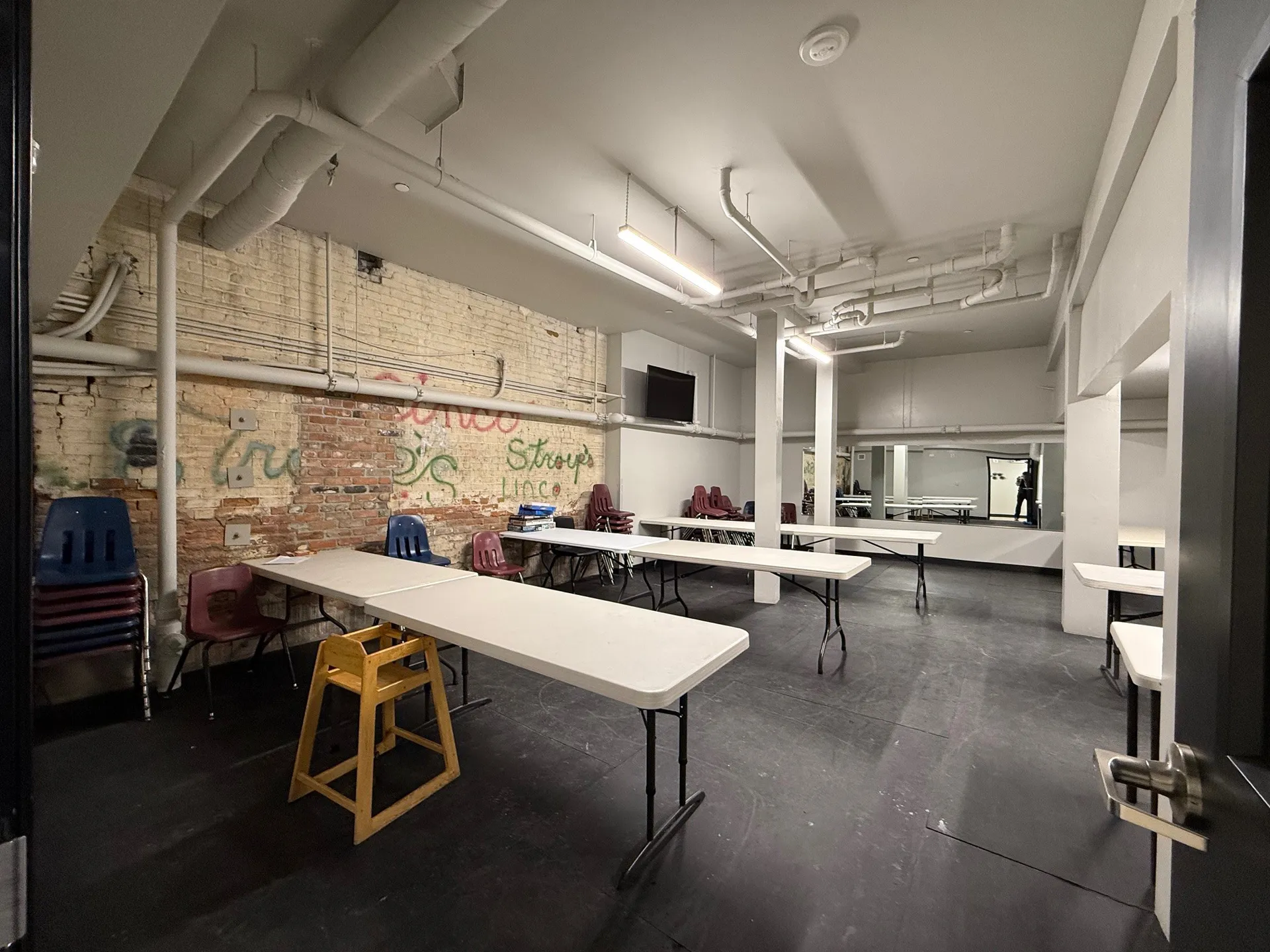Event space with tables, chairs, and industrial decor for meetings or workshops.