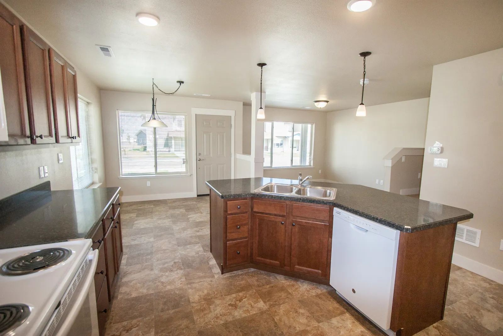 Open-concept kitchen featuring wooden cabinets, granite countertops, and ample natural light.