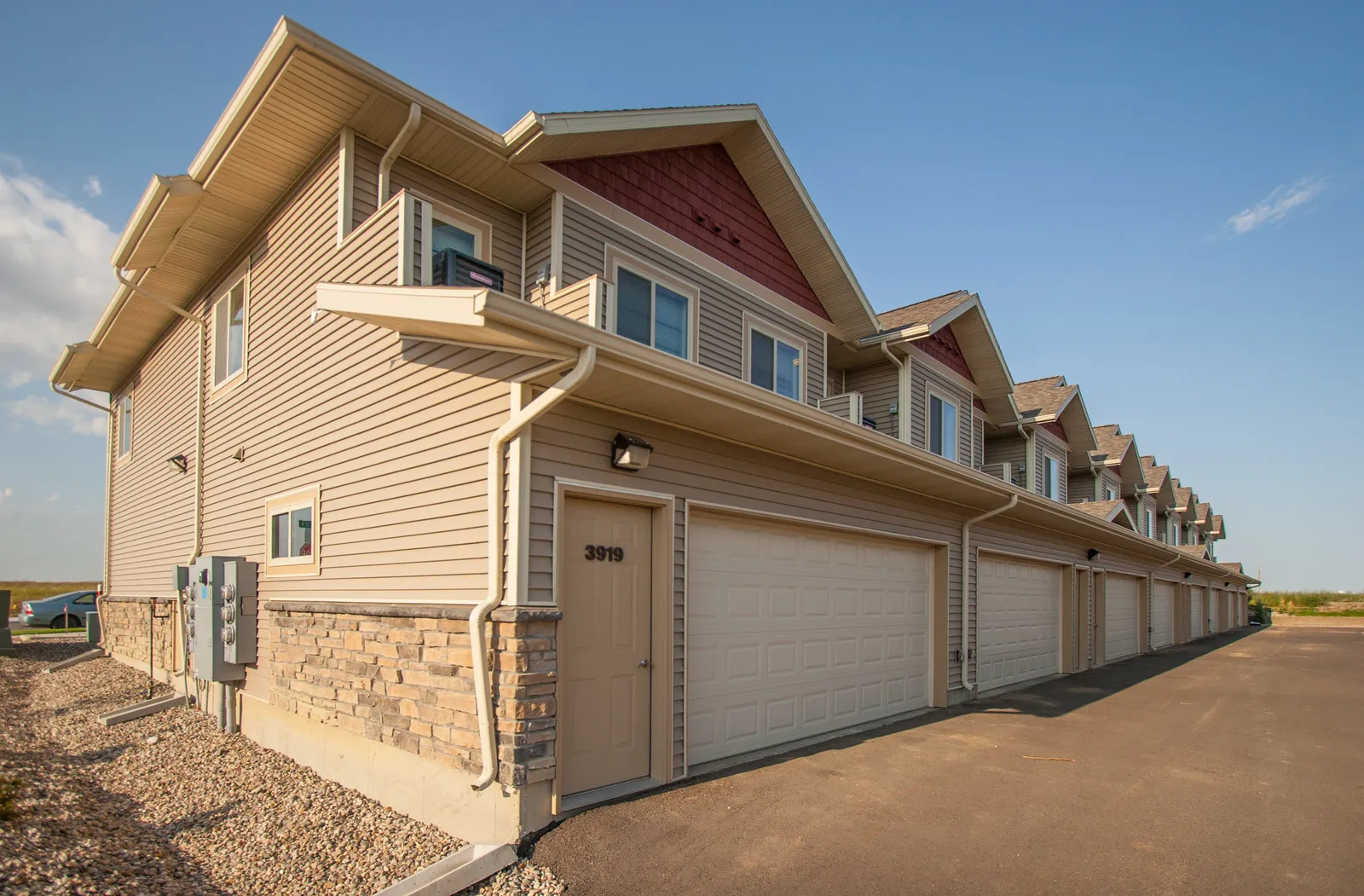 Townhouse row with attached garages, beige siding, and red accents, showcasing modern residential de.