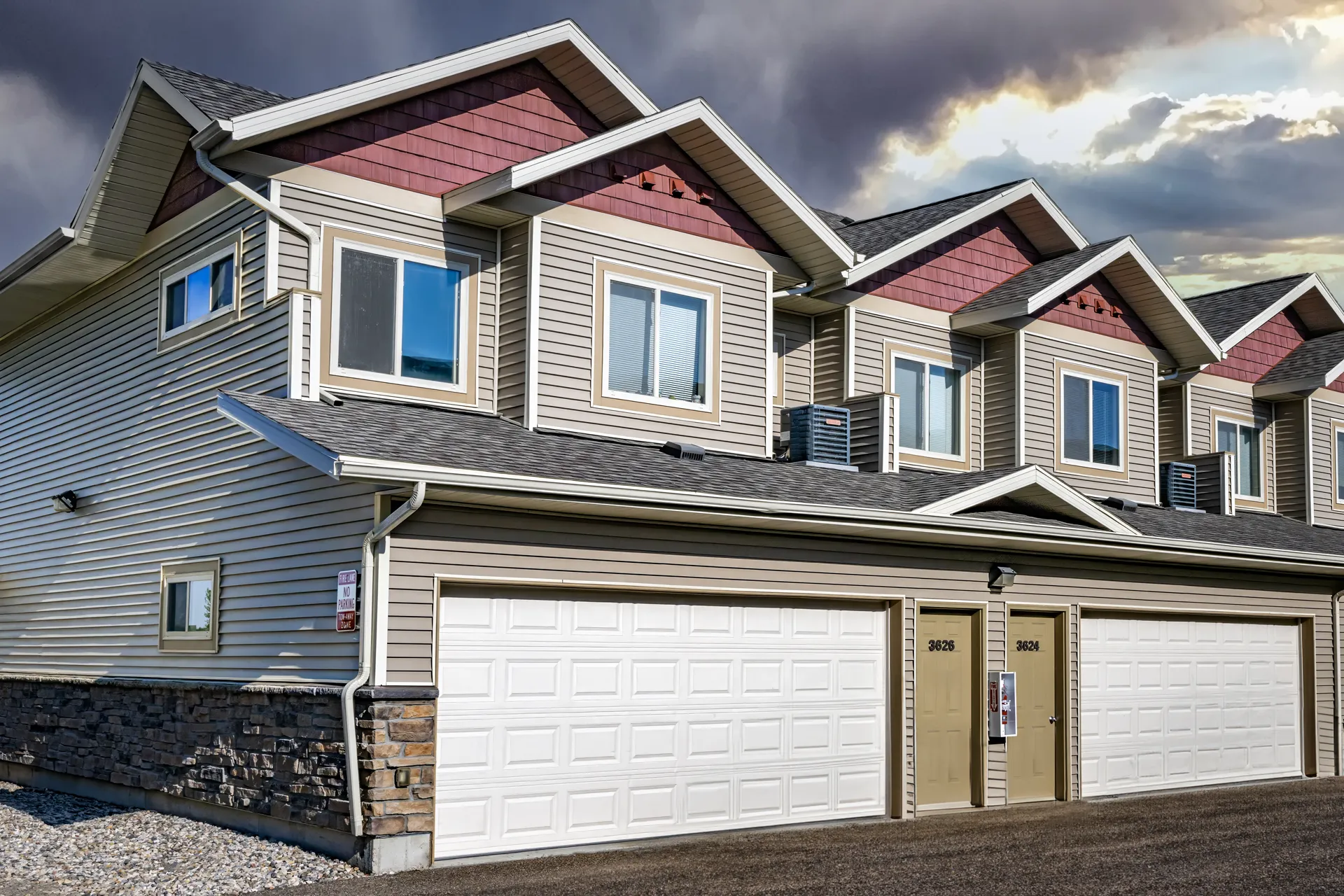 Modern multi-family residential building with garages and colorful gabled roofs.