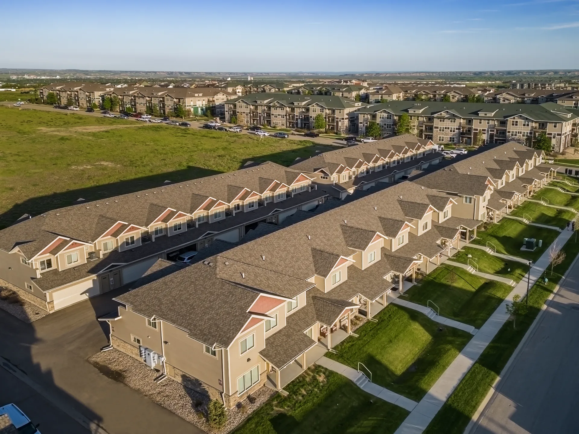 Aerial view of a new residential townhouse complex with green lawns, paved walkways, and uniform arc.