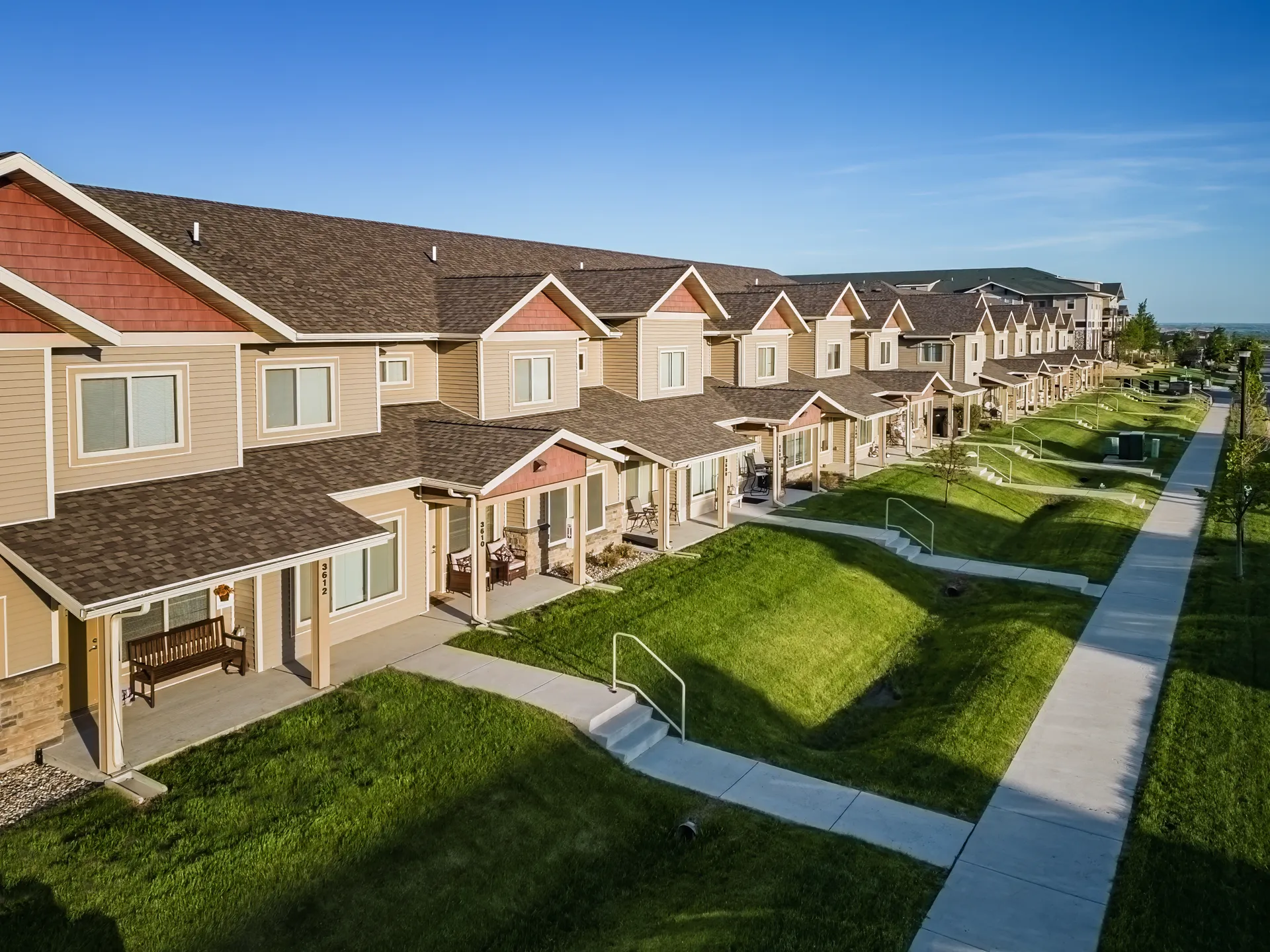 Row of modern townhomes in a well-maintained residential community with lush green lawns.