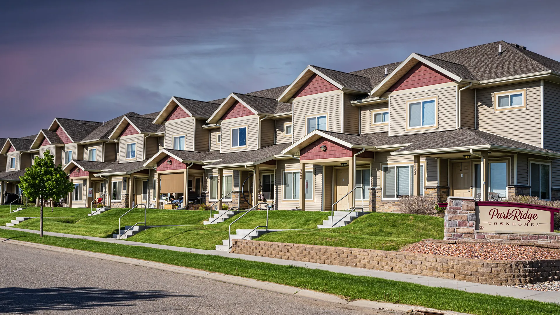 Beautiful row of modern townhouses with well-maintained lawns and sidewalks.