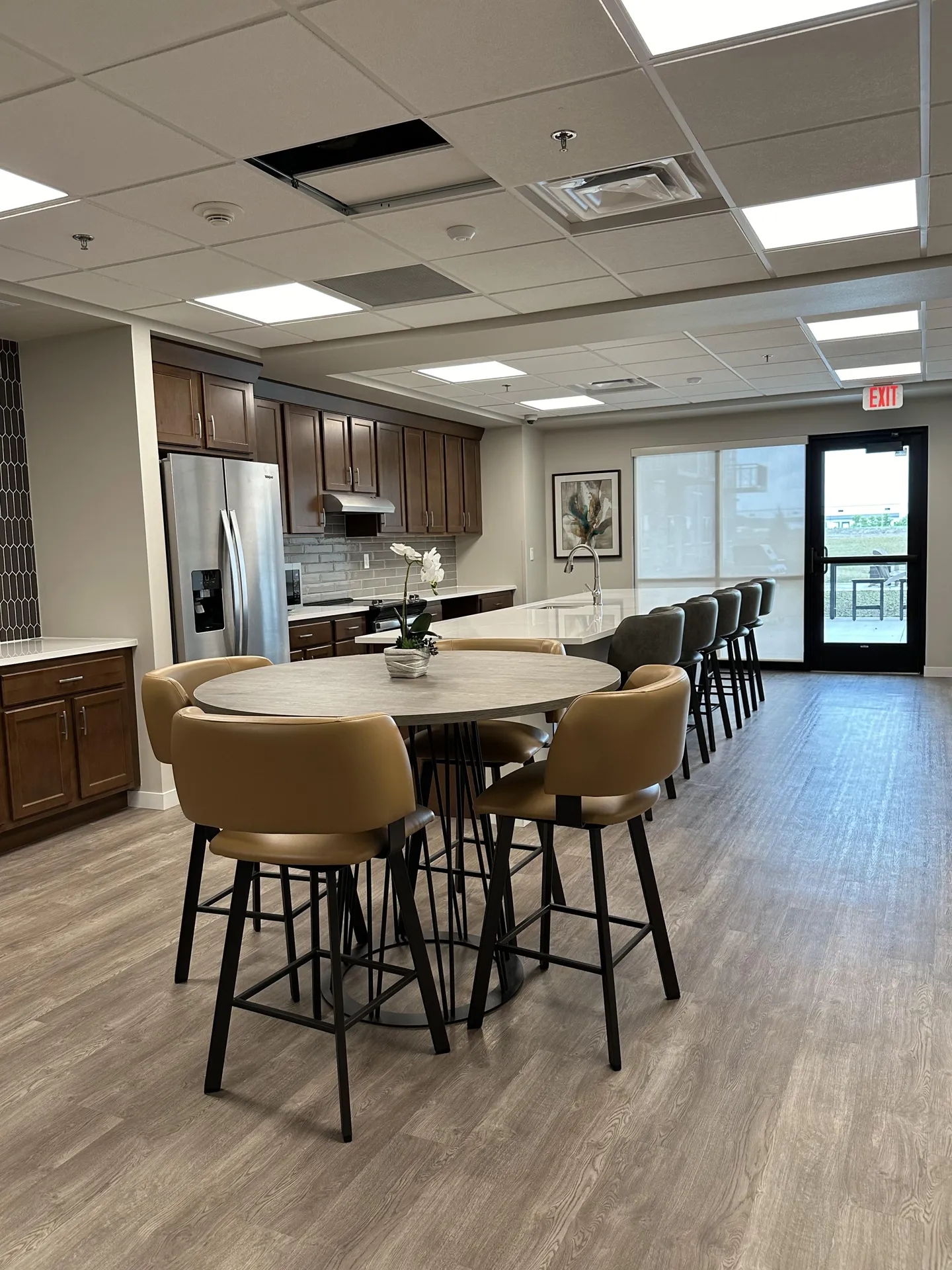 Office break room with kitchen, round table, and comfortable chairs for employees.