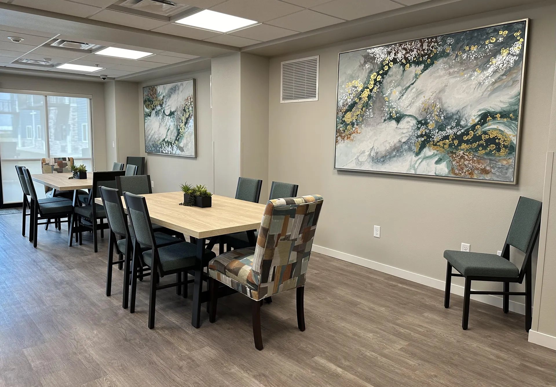 Conference room with contemporary art, wooden tables, and comfortable chairs.
