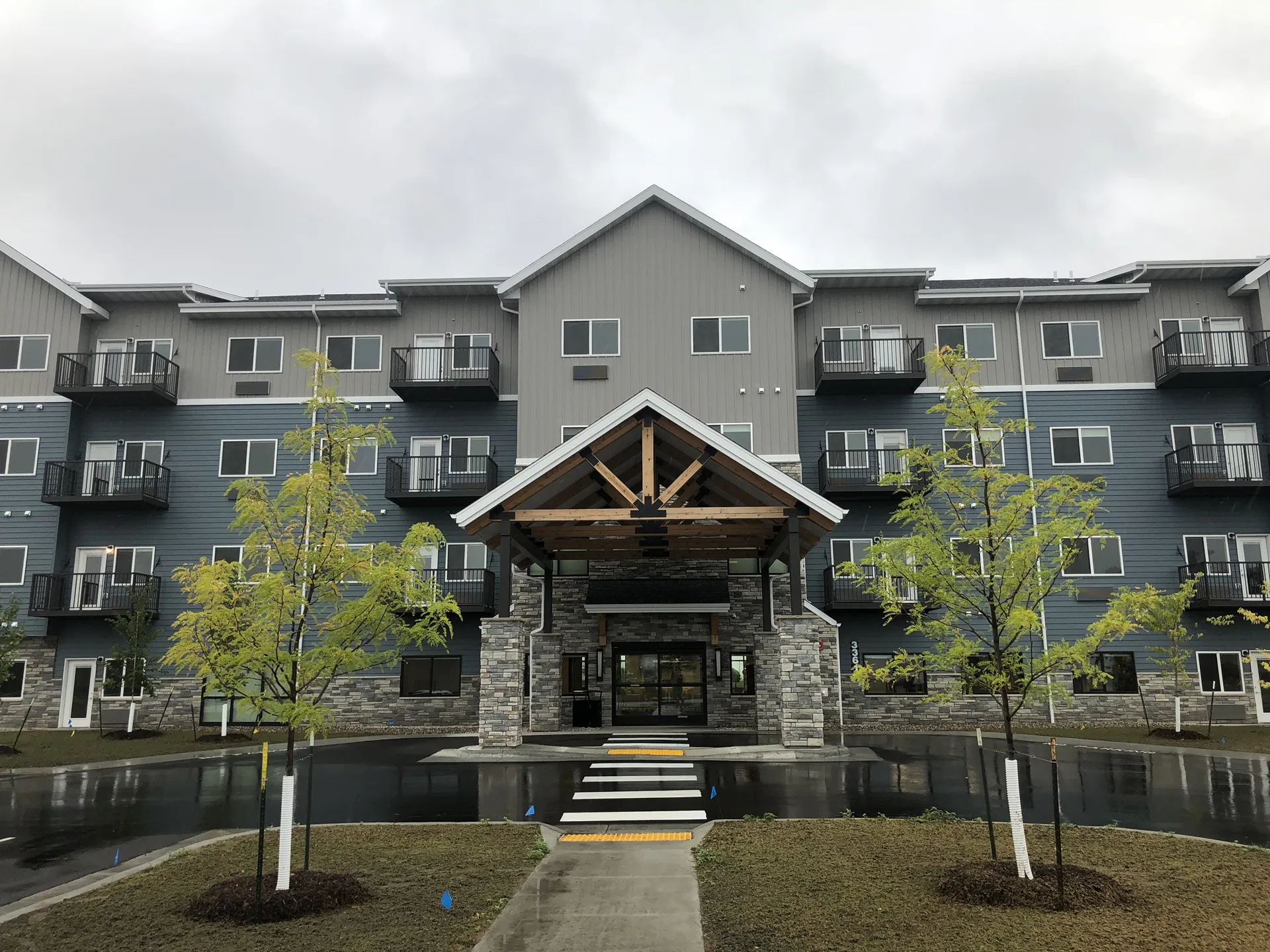Contemporary multi-story apartment complex with landscaped entryway and water features, showcasing q.