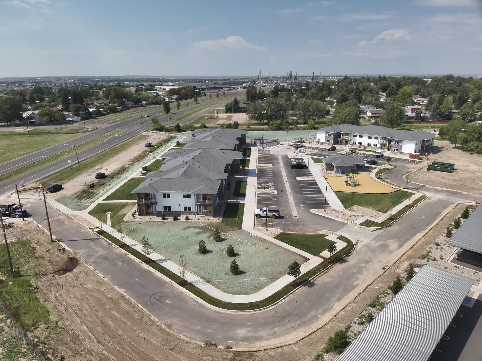 Aerial view of a new apartment complex showcasing landscaped lawns, parking spaces, and surrounding.