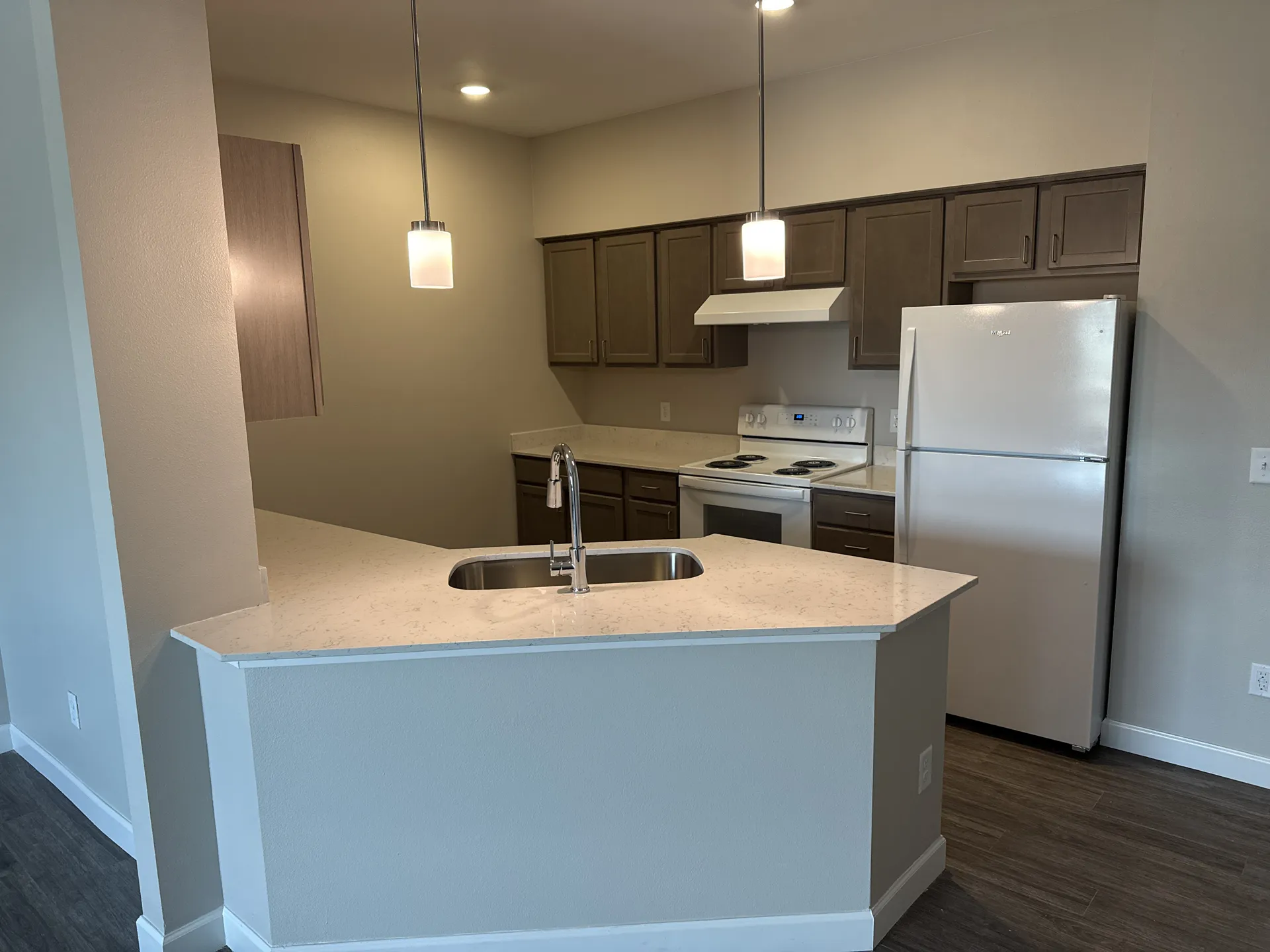 Modern kitchen with white refrigerator, stove, and brown cabinetry for home renovation.