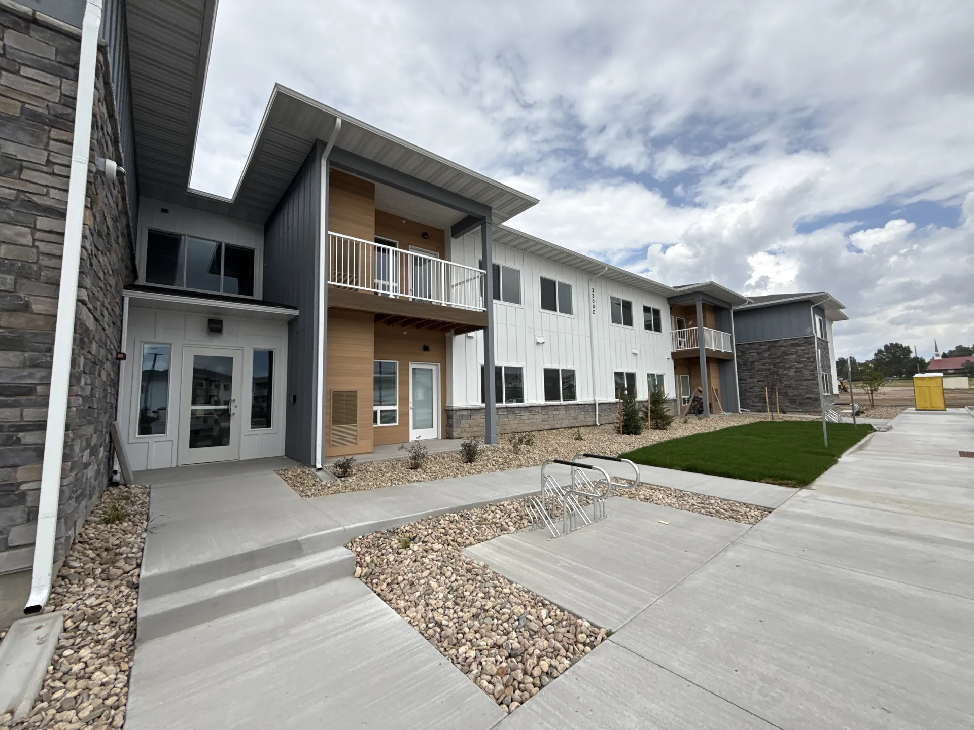 Contemporary apartment complex with balconies, clean design, and outdoor walkways.