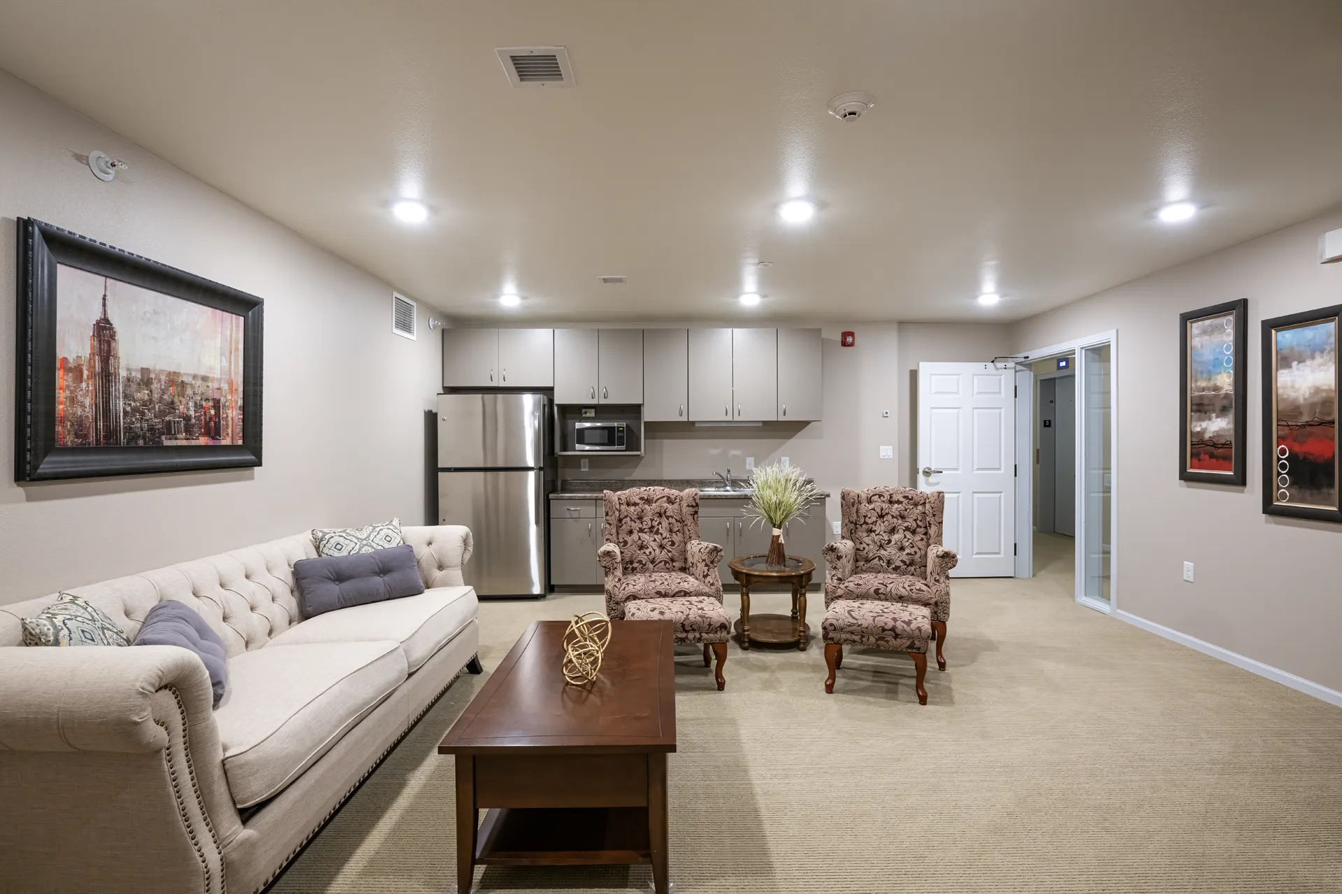 Living room with comfortable sofa, armchairs, and kitchen in the background.