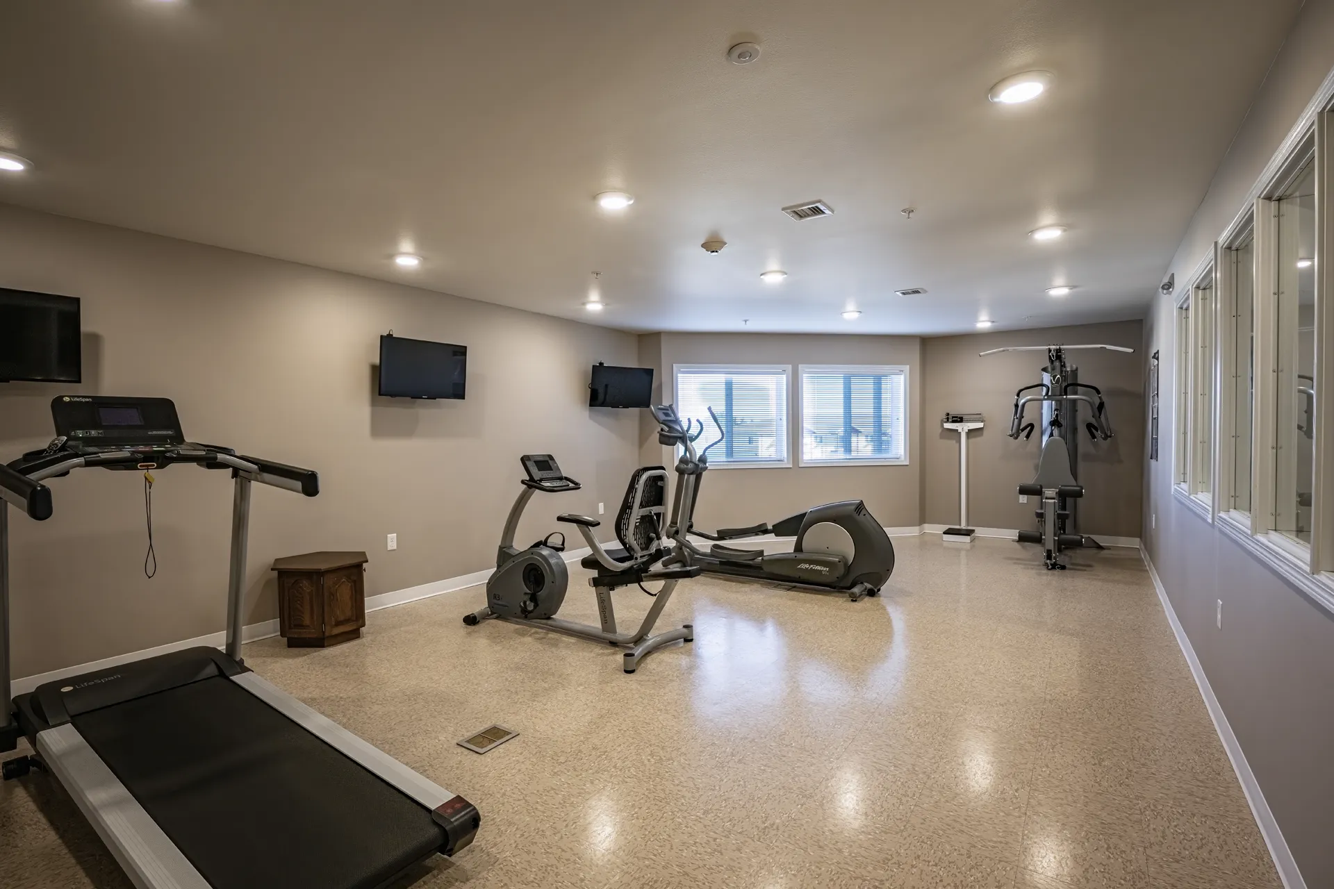 Indoor gym with treadmill, elliptical, and exercise bikes for fitness and training.