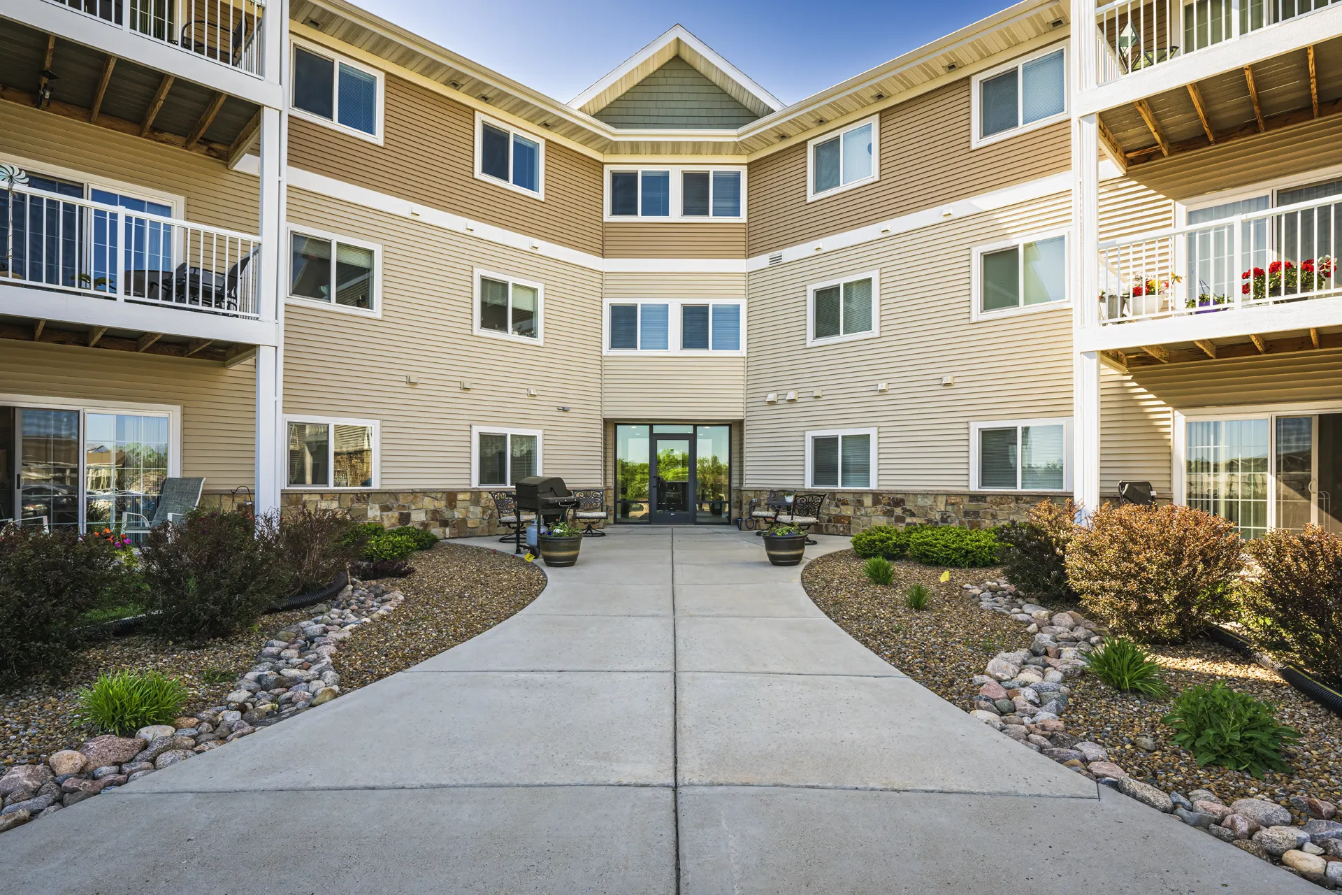 Apartment building with landscaped courtyard, outdoor seating, and modern design.