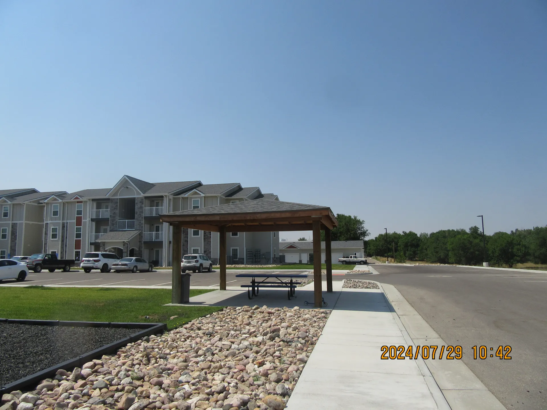 Apartment complex with outdoor pavilion and parking area.