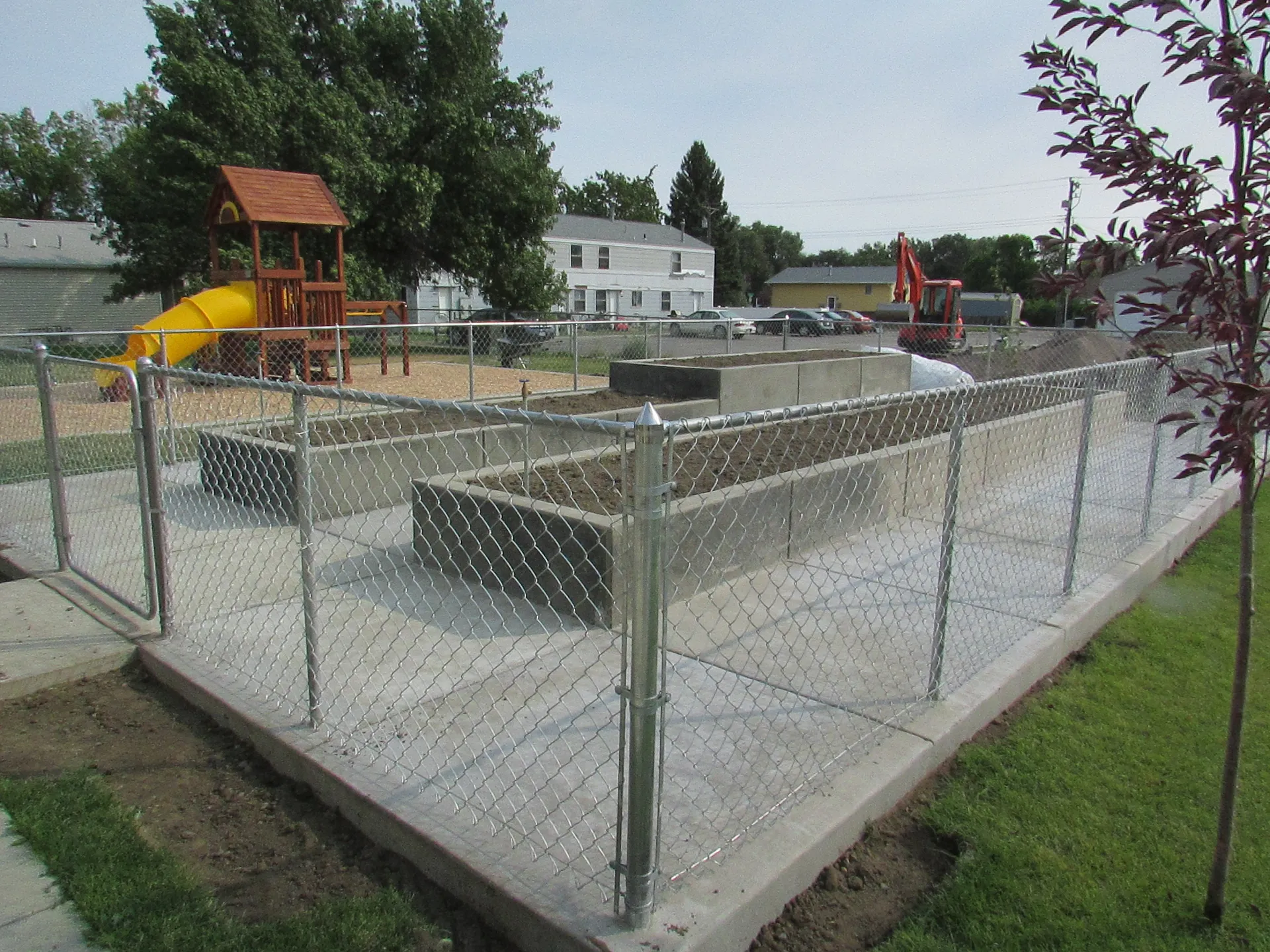 Playground with safety fencing, slide, and play equipment for children.