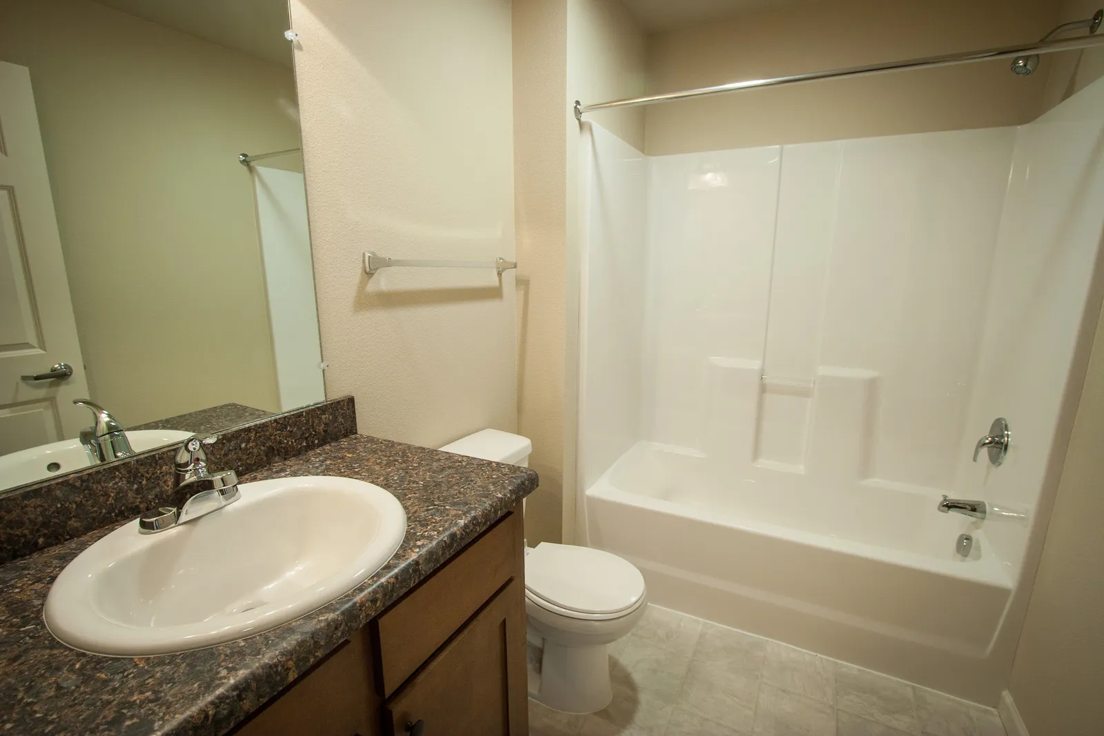 Bathroom with bathtub, toilet, and vanity with granite countertop in a home.